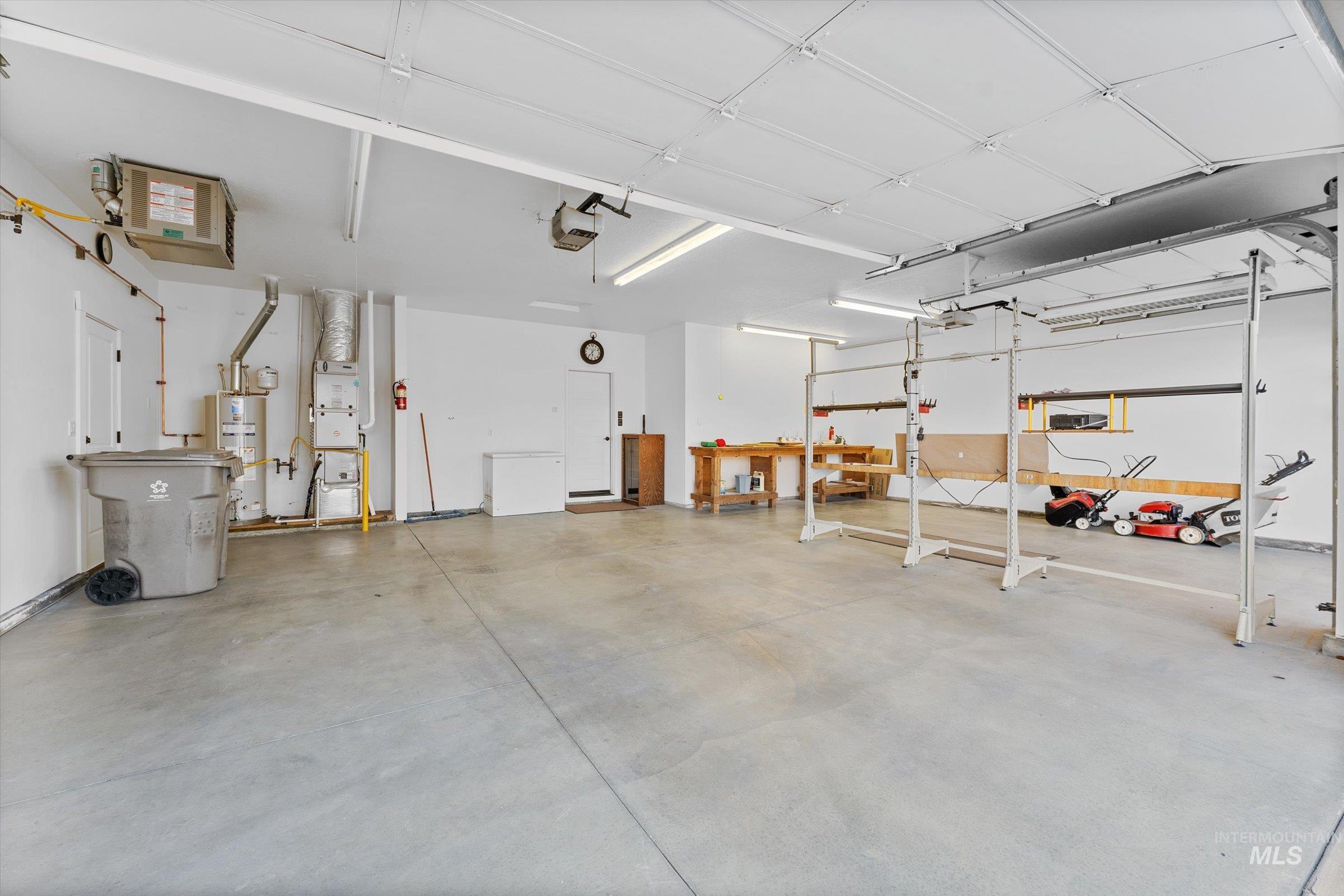 Garage featuring secured water heater, heating unit, and a garage door opener