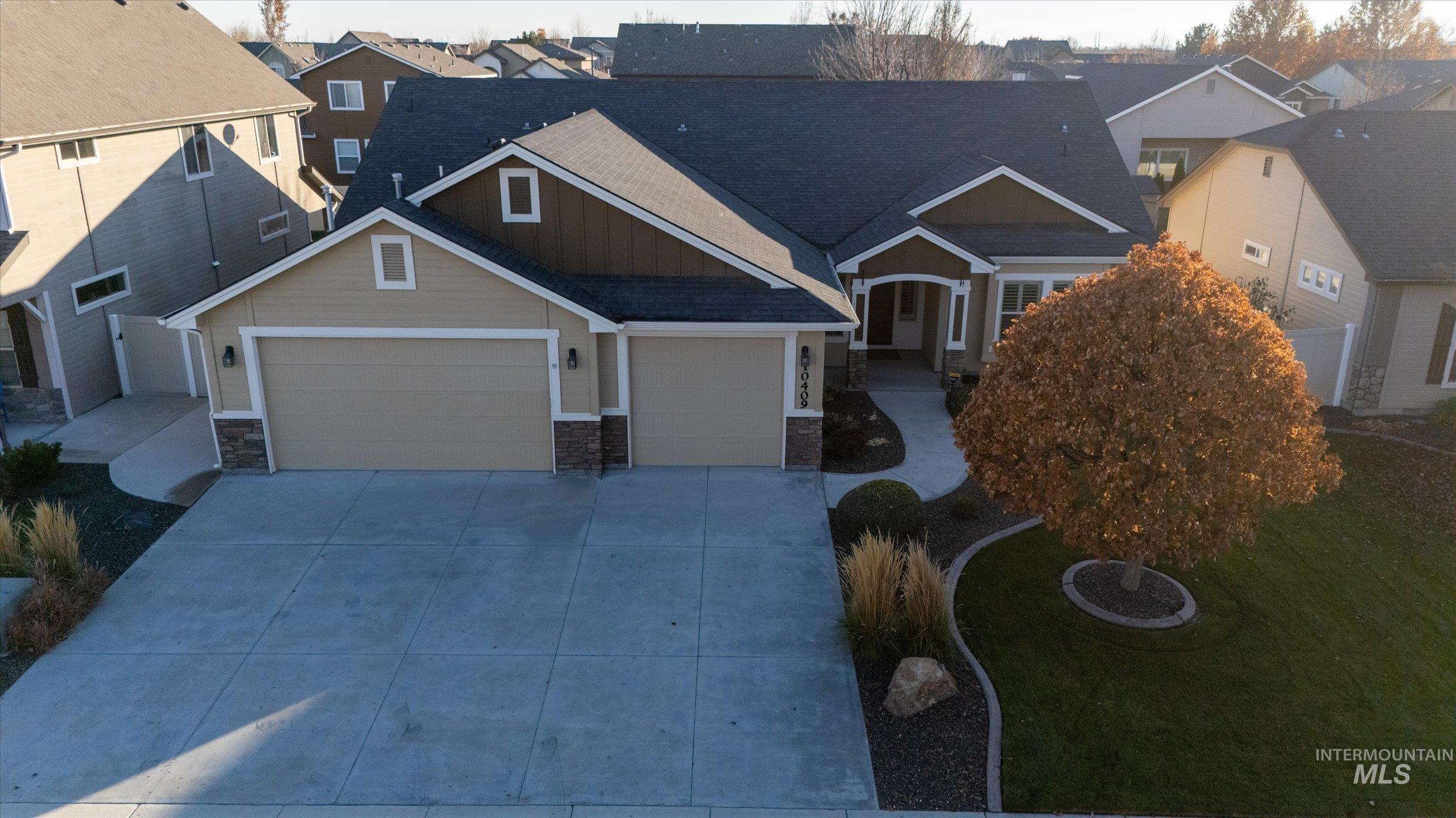 Craftsman inspired home with stone siding, concrete driveway, a garage, board and batten siding, and a residential view