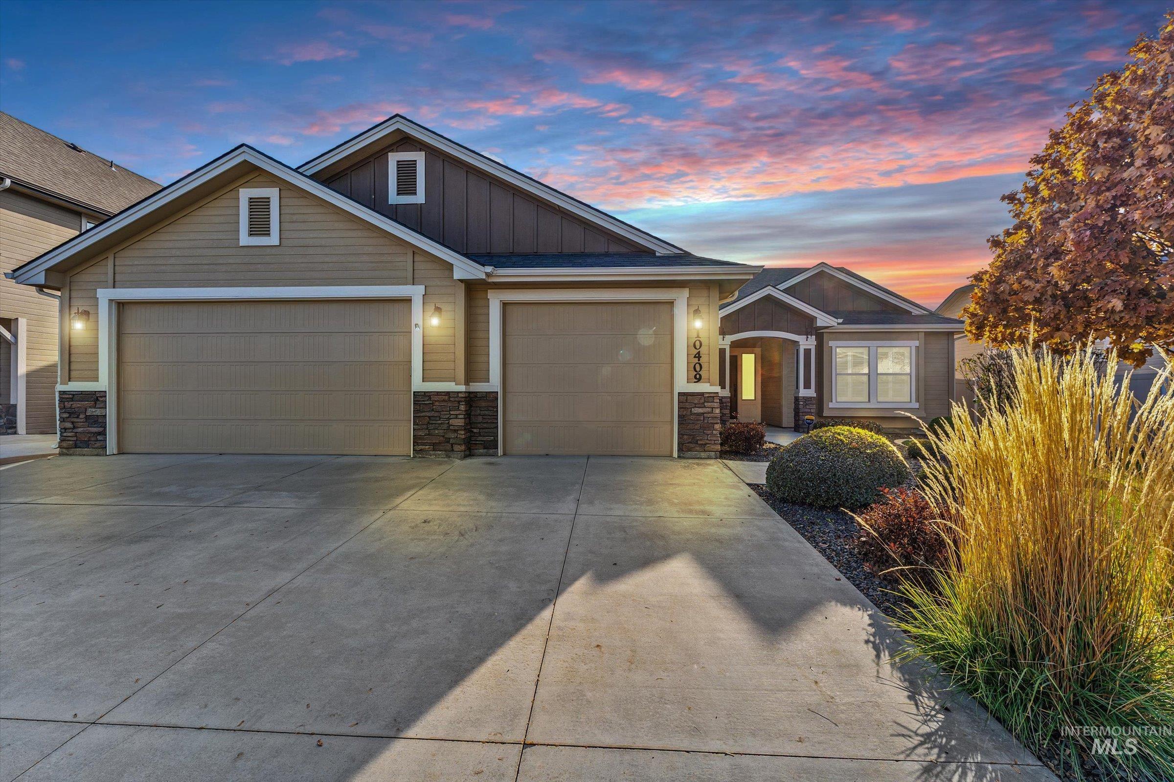 Craftsman-style house with board and batten siding, driveway, stone siding, and an attached garage