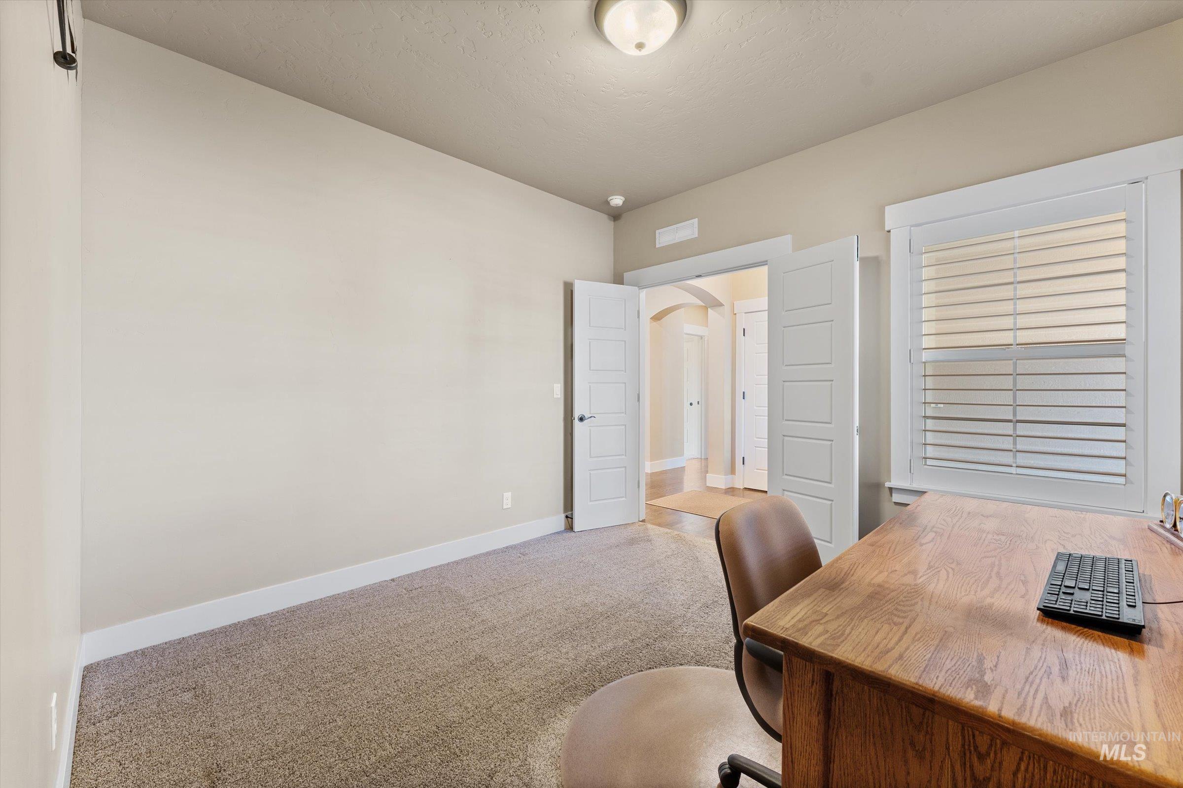 Carpeted office featuring arched walkways and baseboards