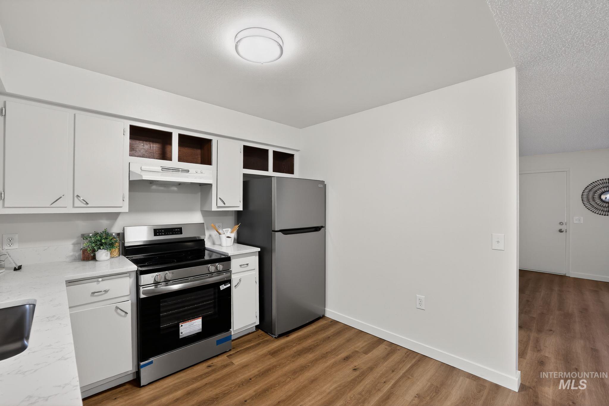 Kitchen featuring white cabinets, stainless steel appliances, dark wood-style floors, and a textured ceiling