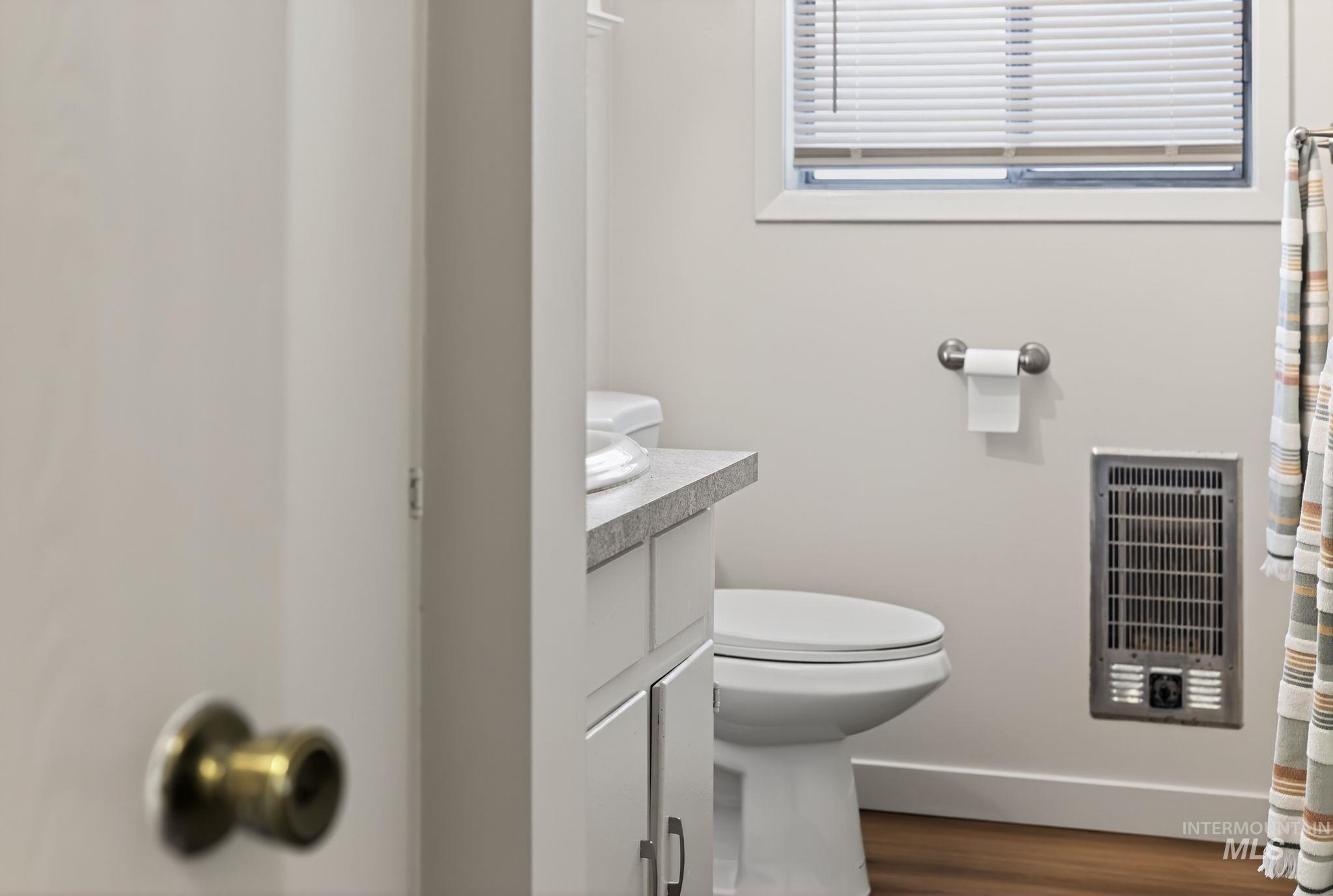 Bathroom featuring heating unit, vanity, curtained shower, and dark wood-style floors