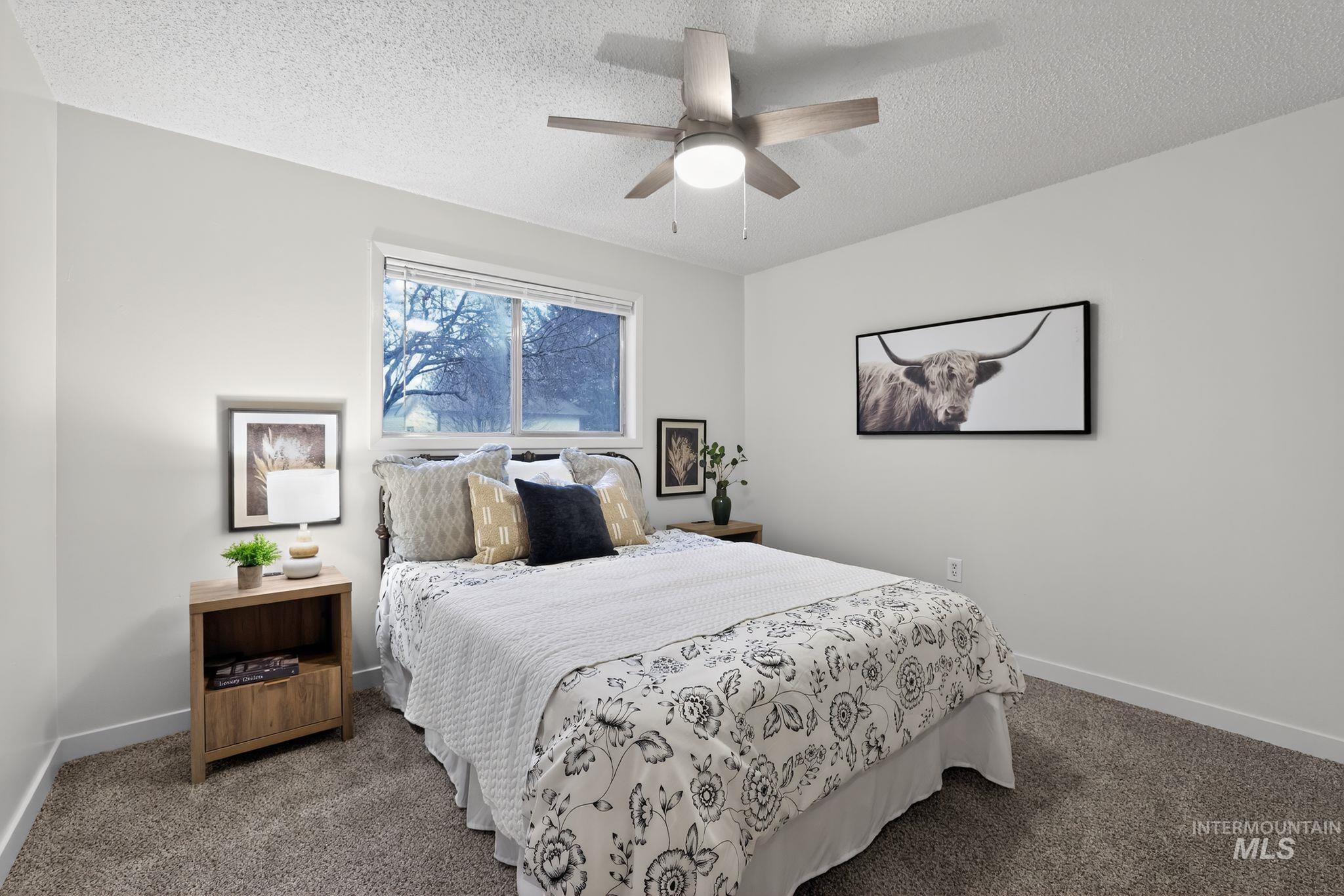Carpeted bedroom with ceiling fan and a textured ceiling