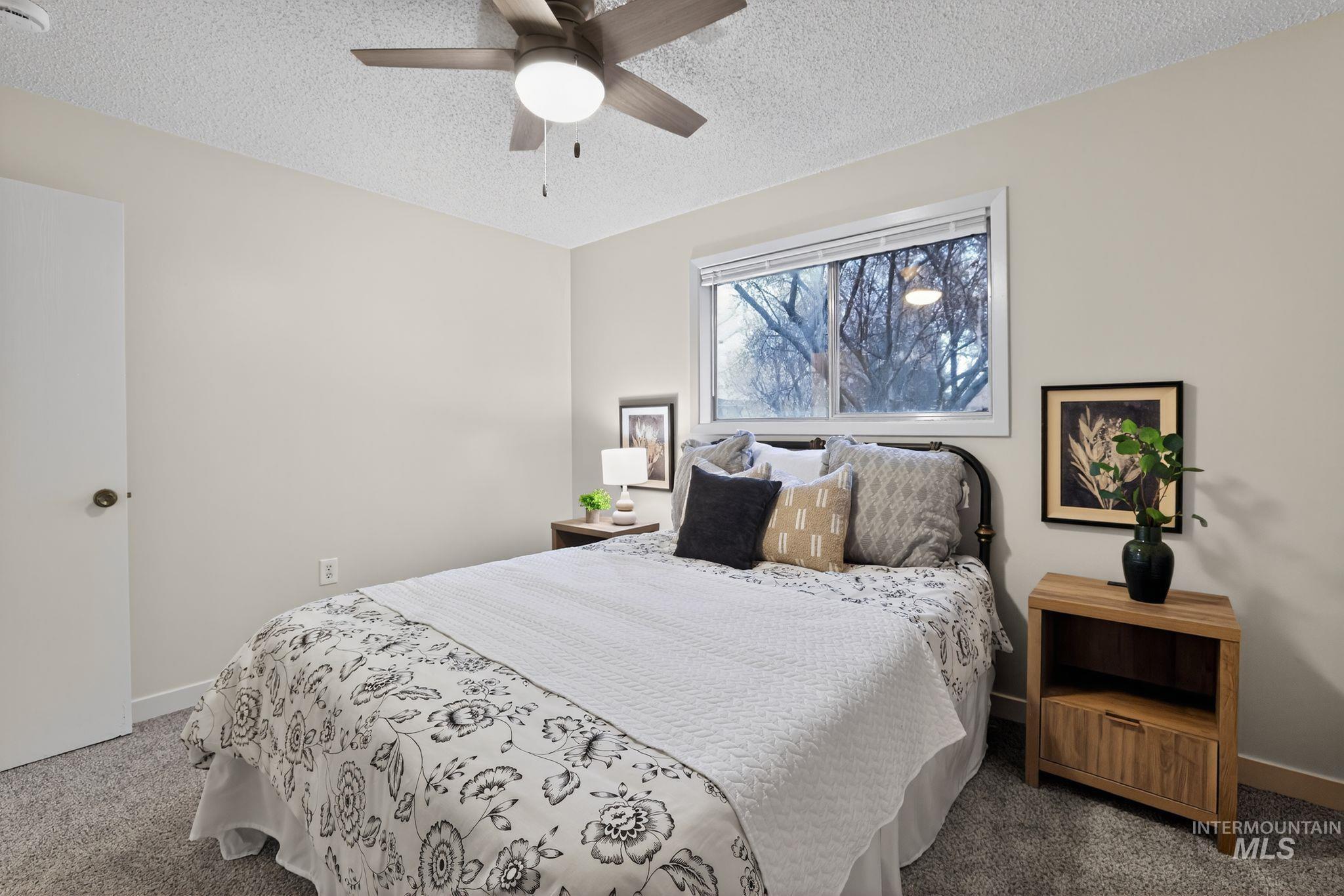 Carpeted bedroom featuring a textured ceiling and a ceiling fan