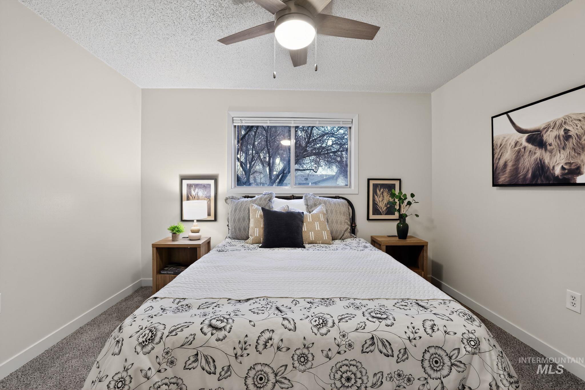 Bedroom with dark colored carpet, ceiling fan, and a textured ceiling