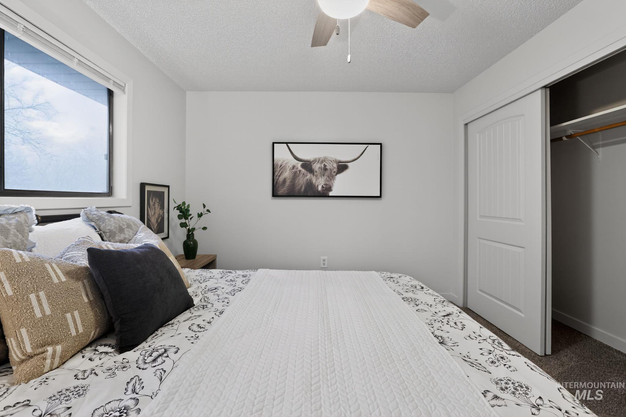 Carpeted bedroom featuring a textured ceiling, ceiling fan, and a closet