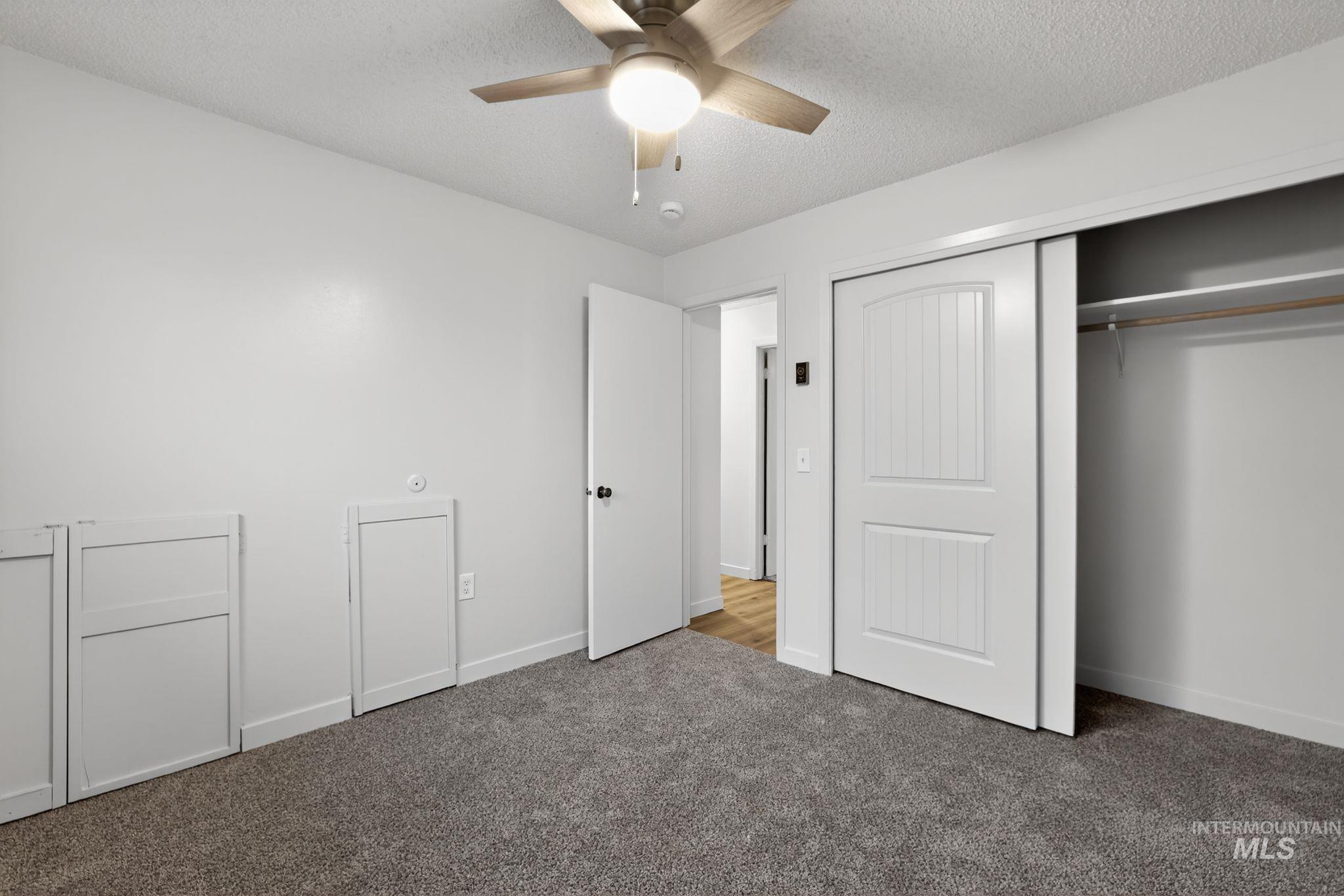 Unfurnished bedroom with a textured ceiling, ceiling fan, carpet, and a closet