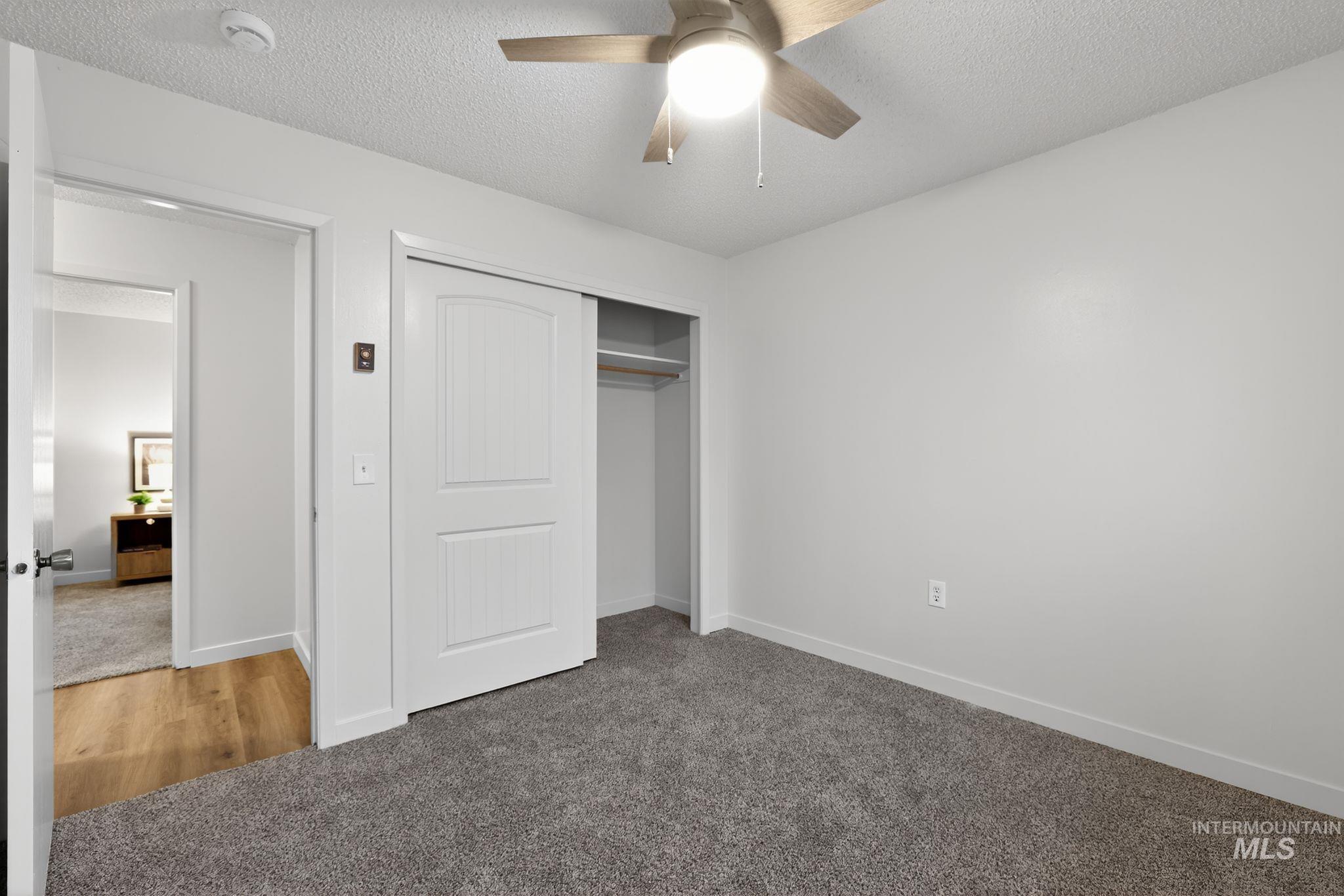 Unfurnished bedroom with carpet flooring, a textured ceiling, a closet, and ceiling fan