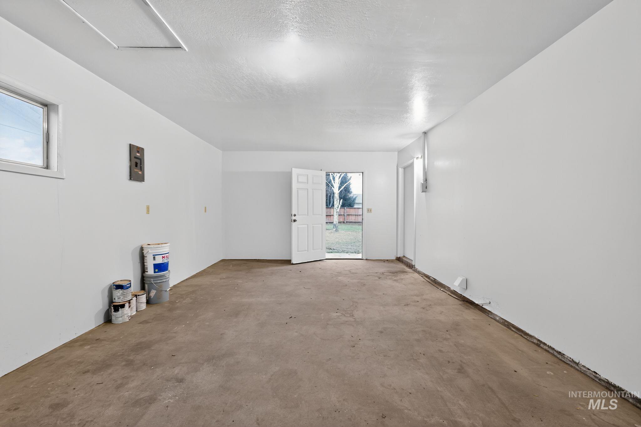 Unfurnished room featuring unfinished concrete floors, a textured ceiling, and electric panel