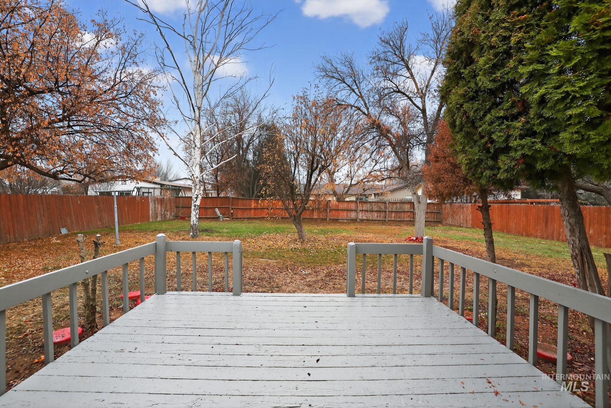 Wooden terrace with a fenced backyard