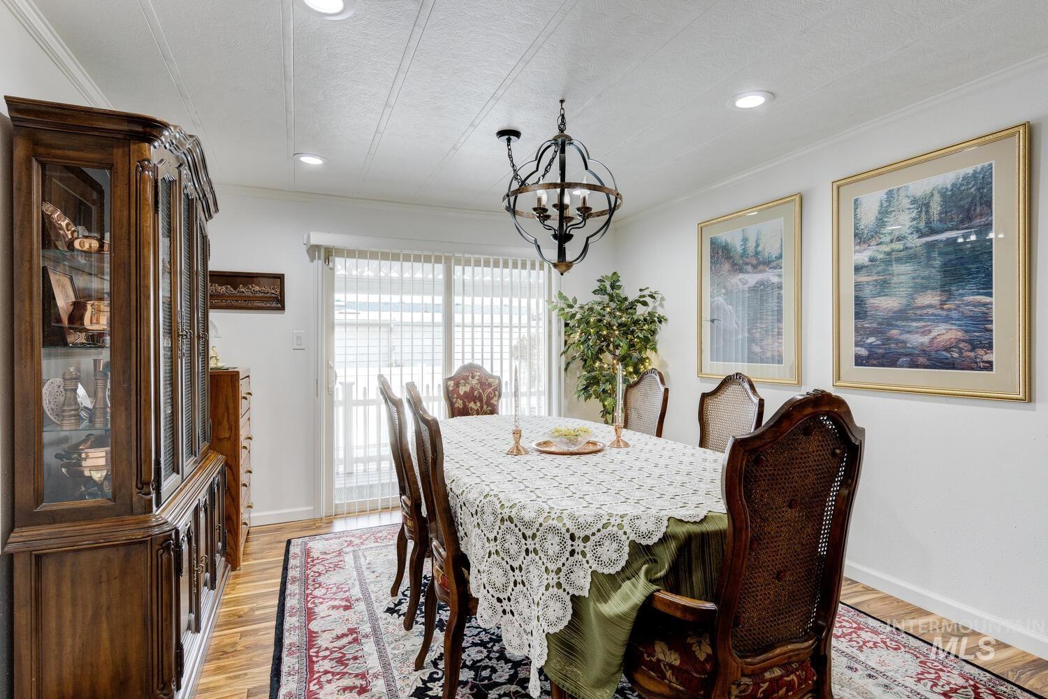 Dining room featuring light wood finished floors, a chandelier, recessed lighting, crown molding, and a textured ceiling