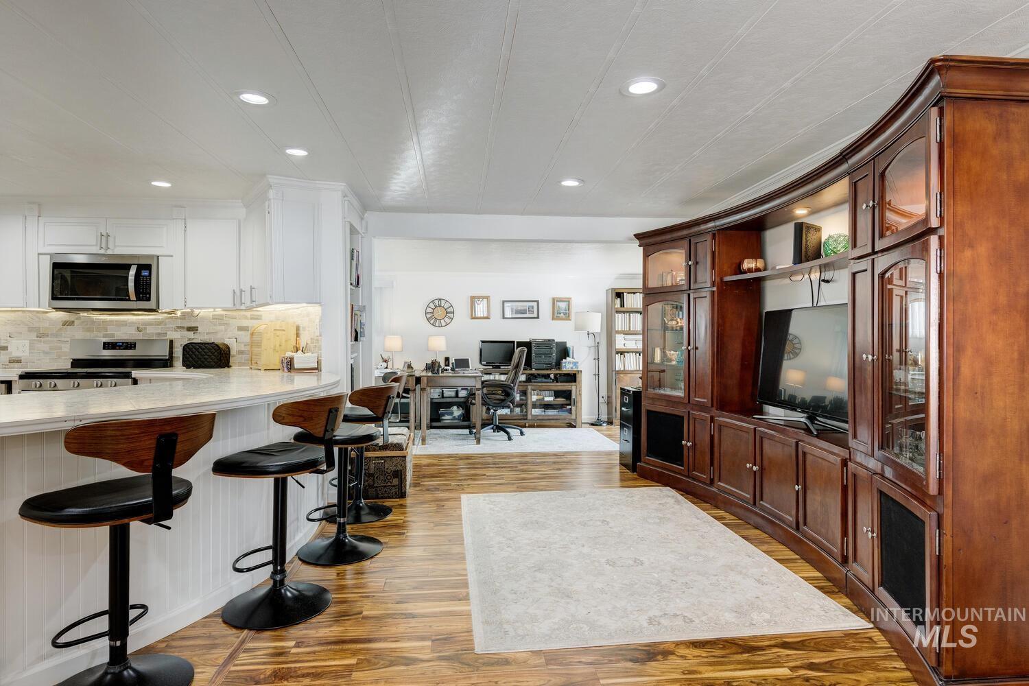 Kitchen featuring a breakfast bar area, an office area, appliances with stainless steel finishes, dark wood-style flooring, and open floor plan