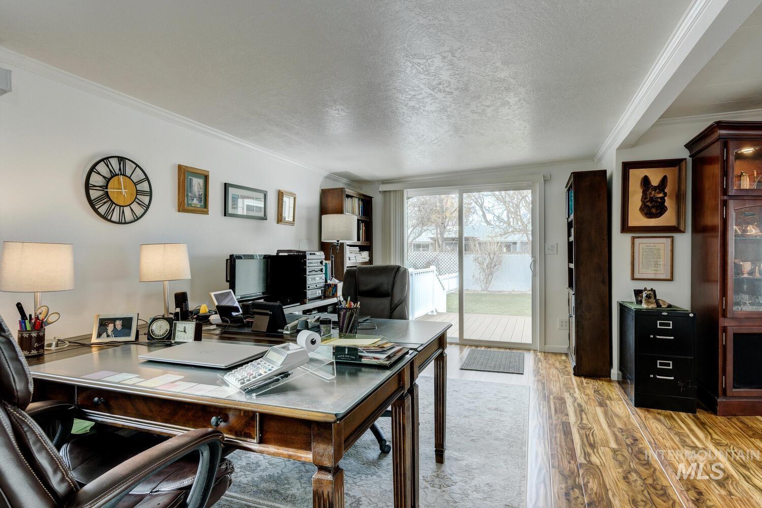Office area featuring a textured ceiling, light wood-style flooring, and ornamental molding