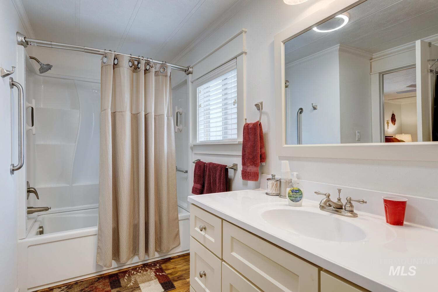 Bathroom with shower / bath combo with shower curtain, crown molding, vanity, and light wood finished floors