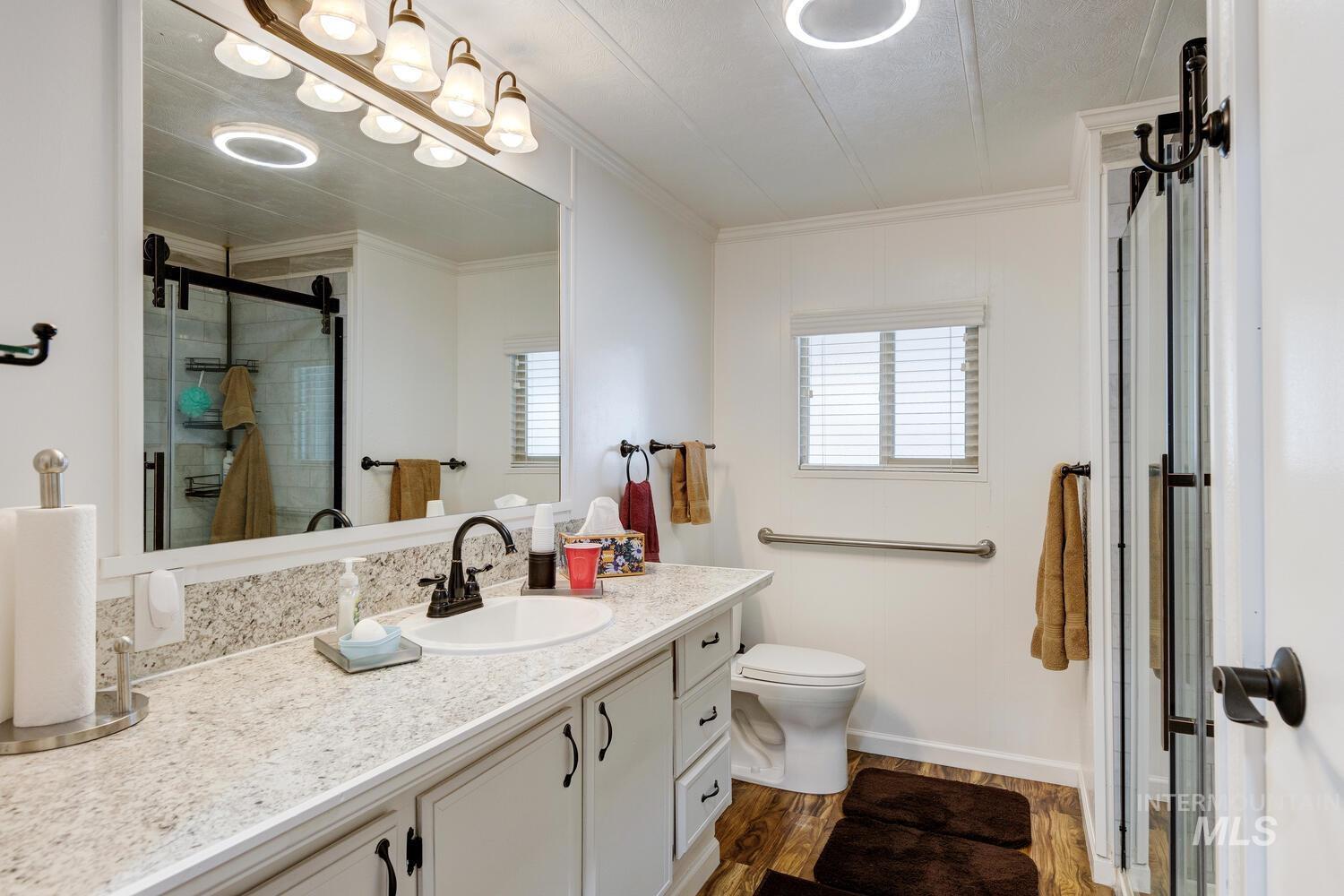 Bathroom with vanity, dark wood-style floors, a stall shower, and crown molding