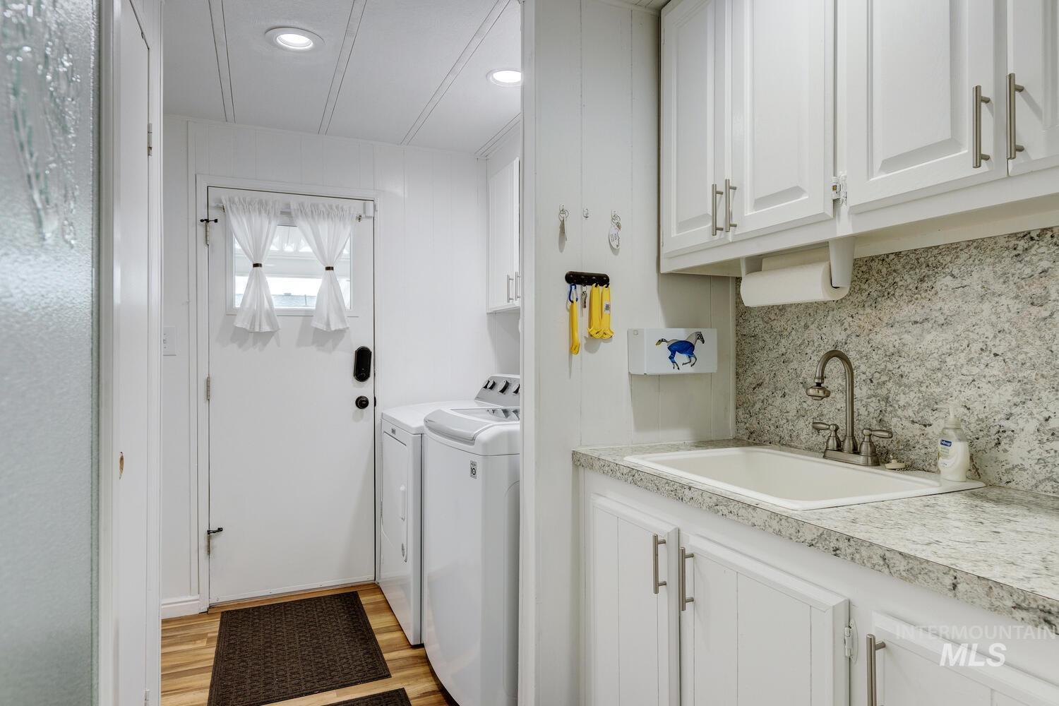 Washroom with independent washer and dryer, cabinet space, and light wood-style floors