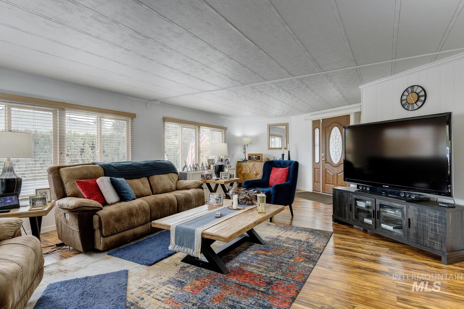 Living room with healthy amount of natural light, wood finished floors, and crown molding