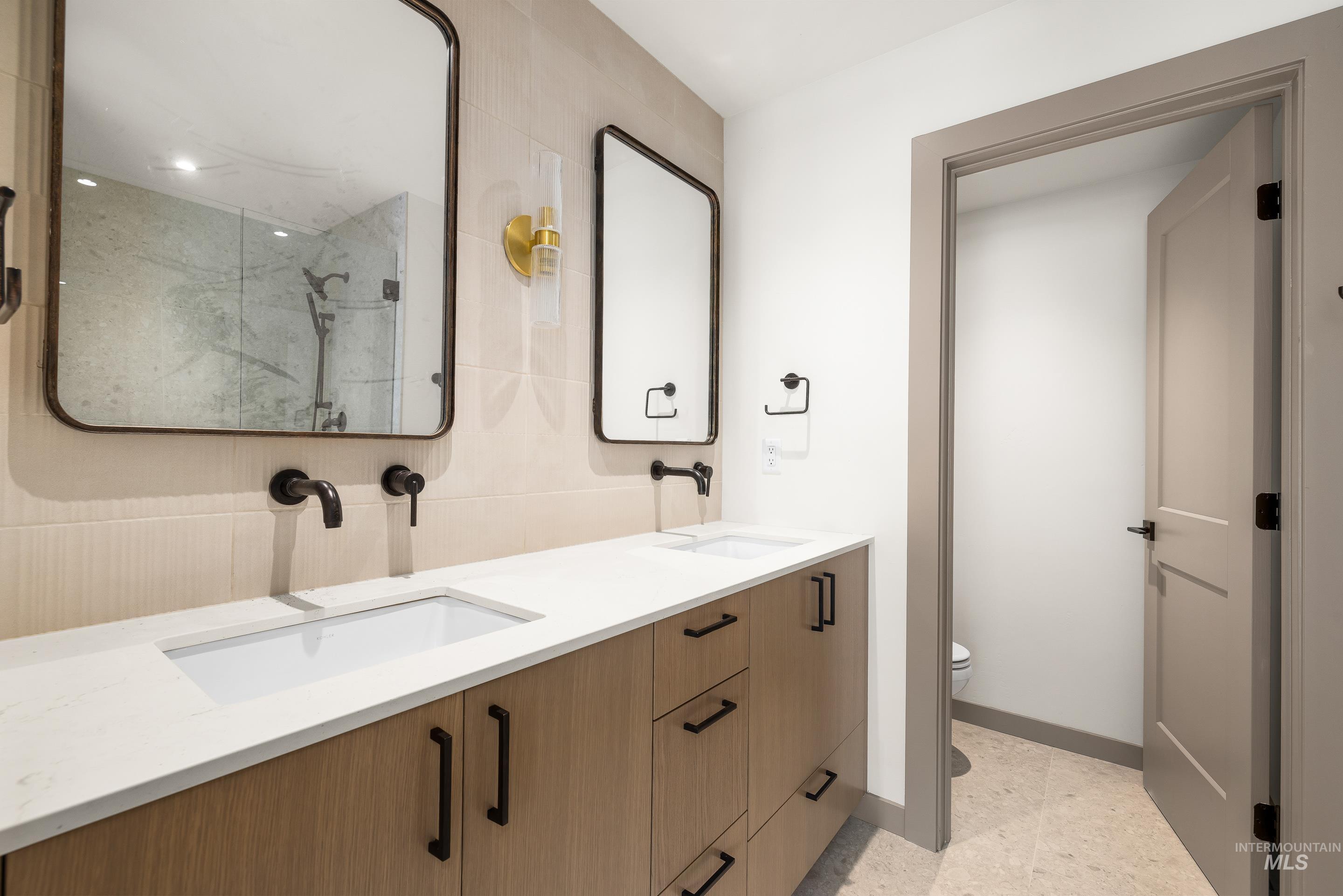 Full bath with a marble finish shower and double vanity