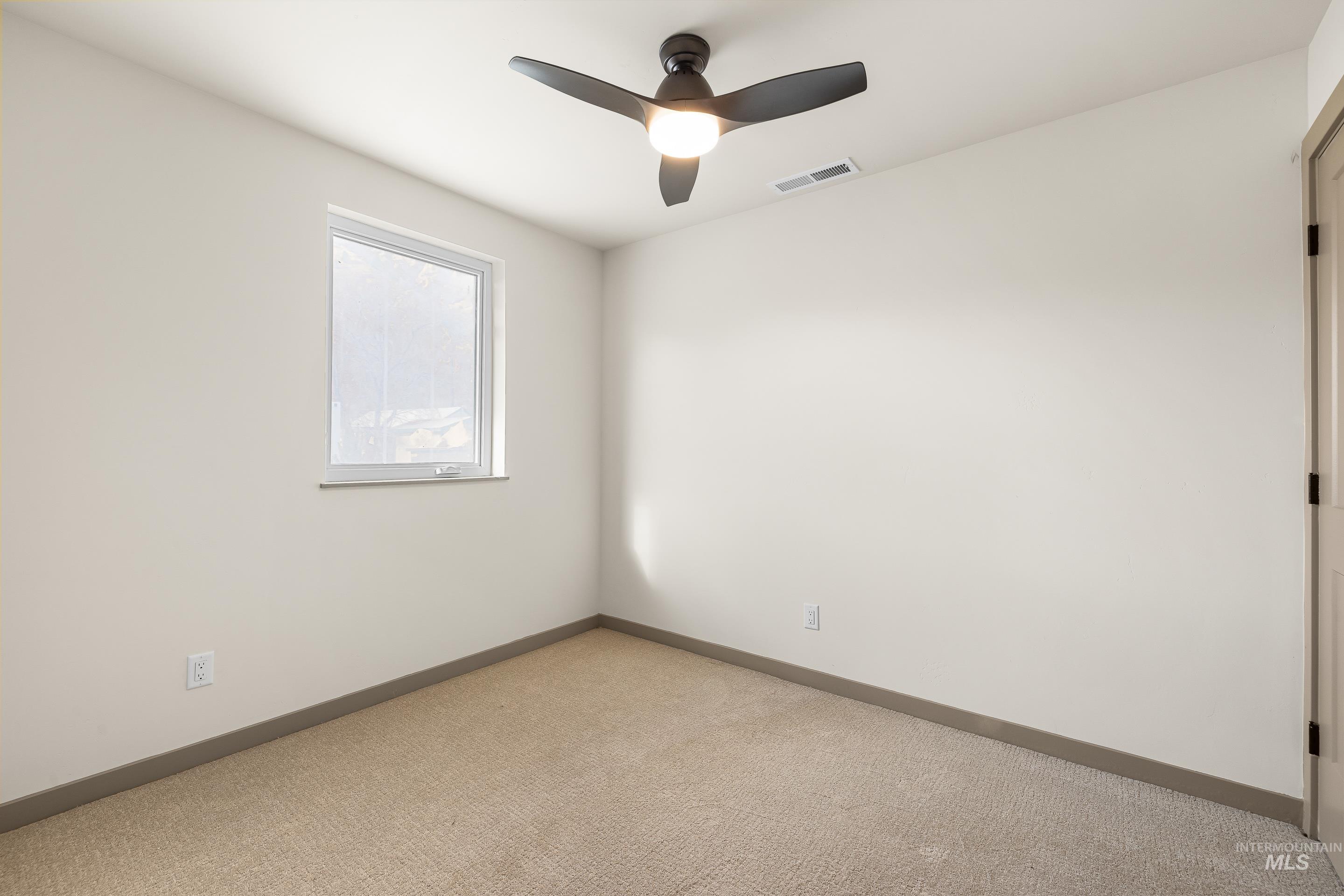 Empty room with ceiling fan and carpet flooring