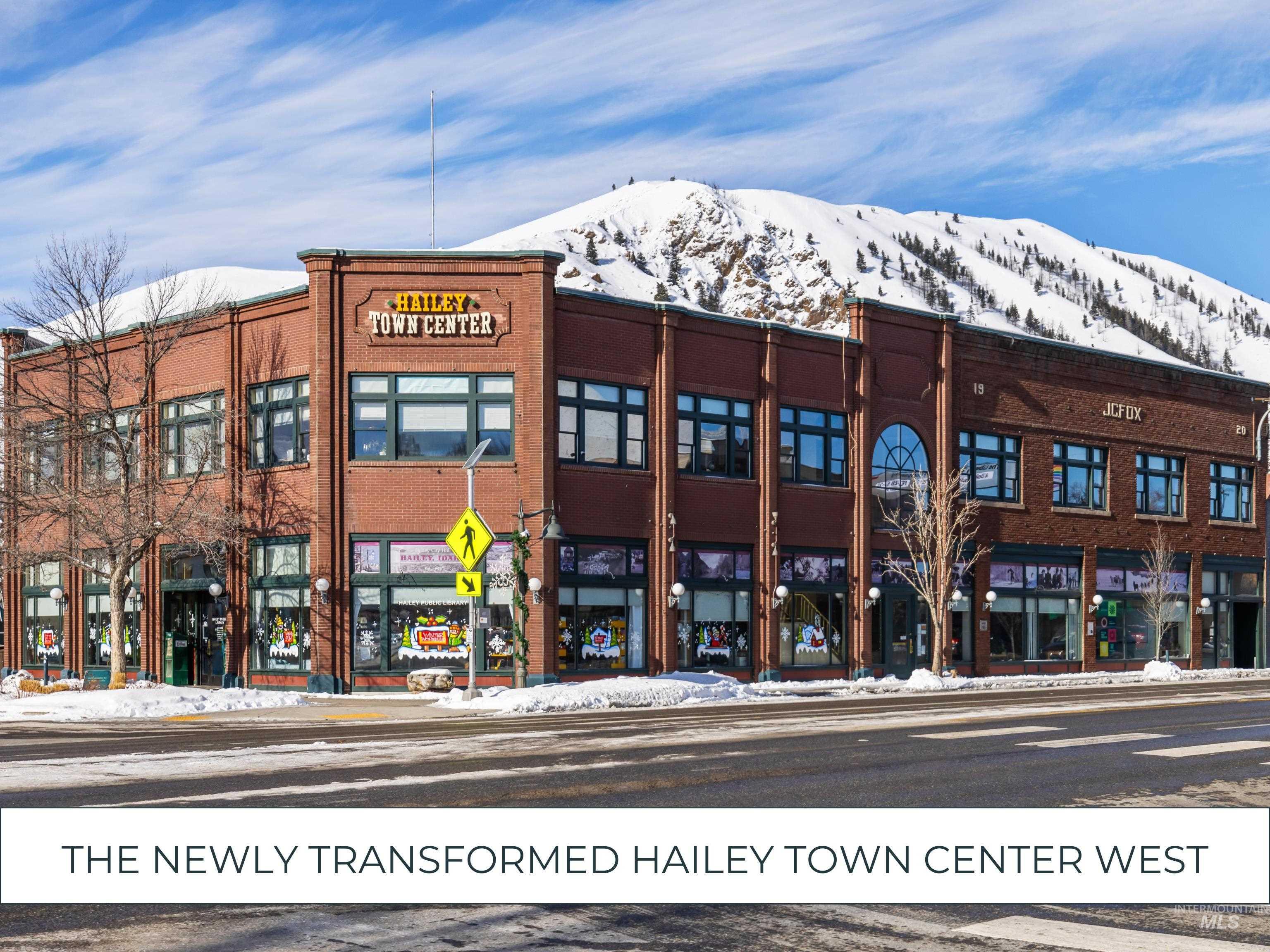 Snow covered building featuring view of commercial area and a mountain view
