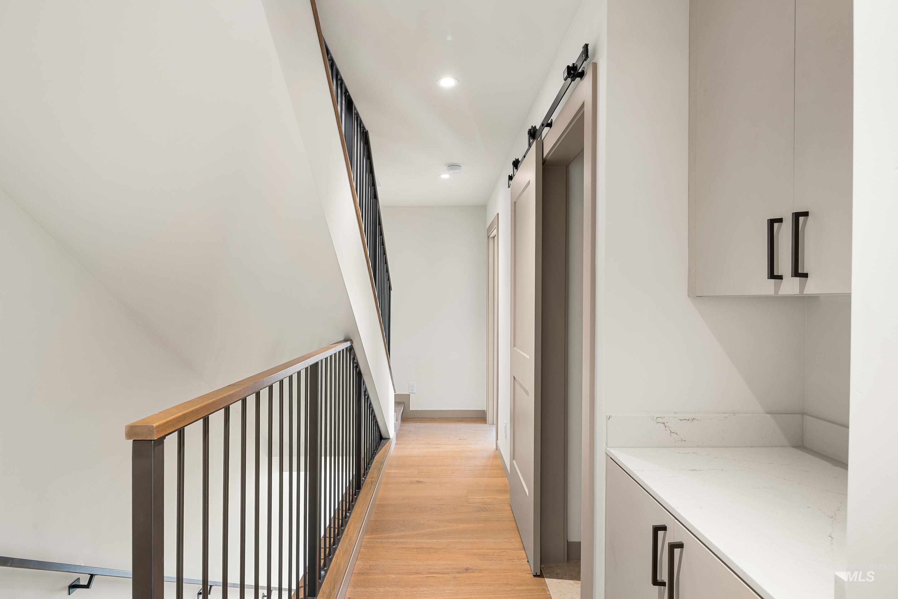 Corridor with light wood-style floors, a barn door, and recessed lighting