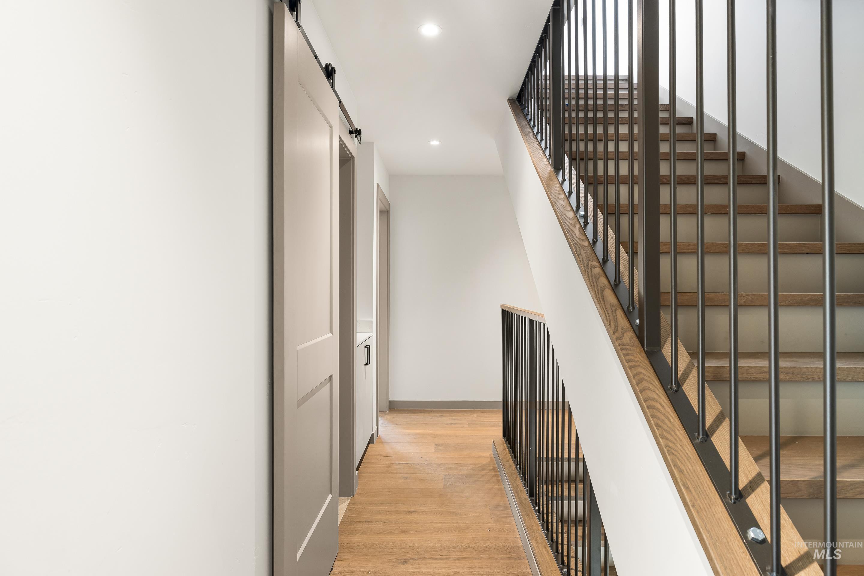 Stairs featuring a barn door, recessed lighting, and wood finished floors