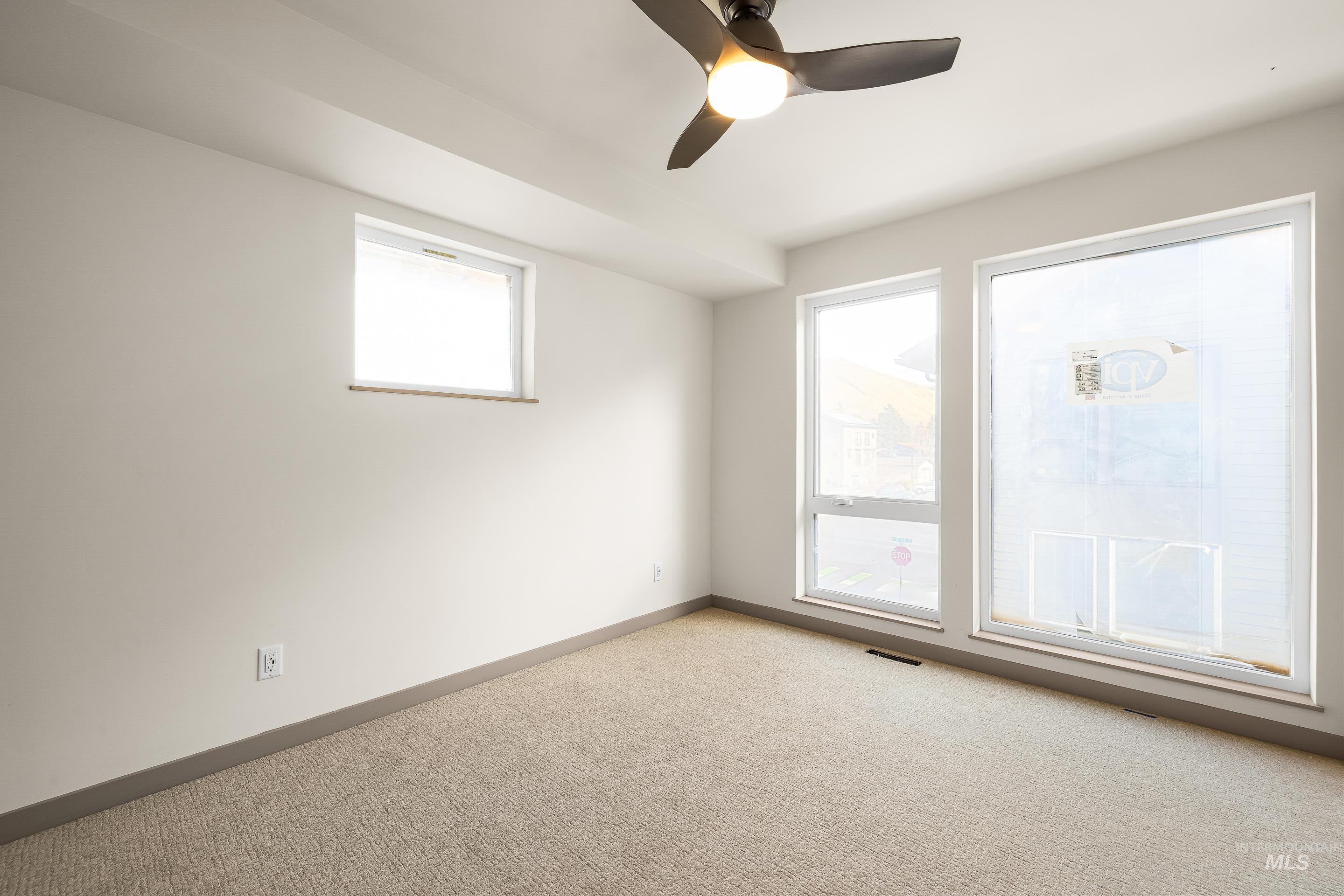 Unfurnished room with ceiling fan and light colored carpet