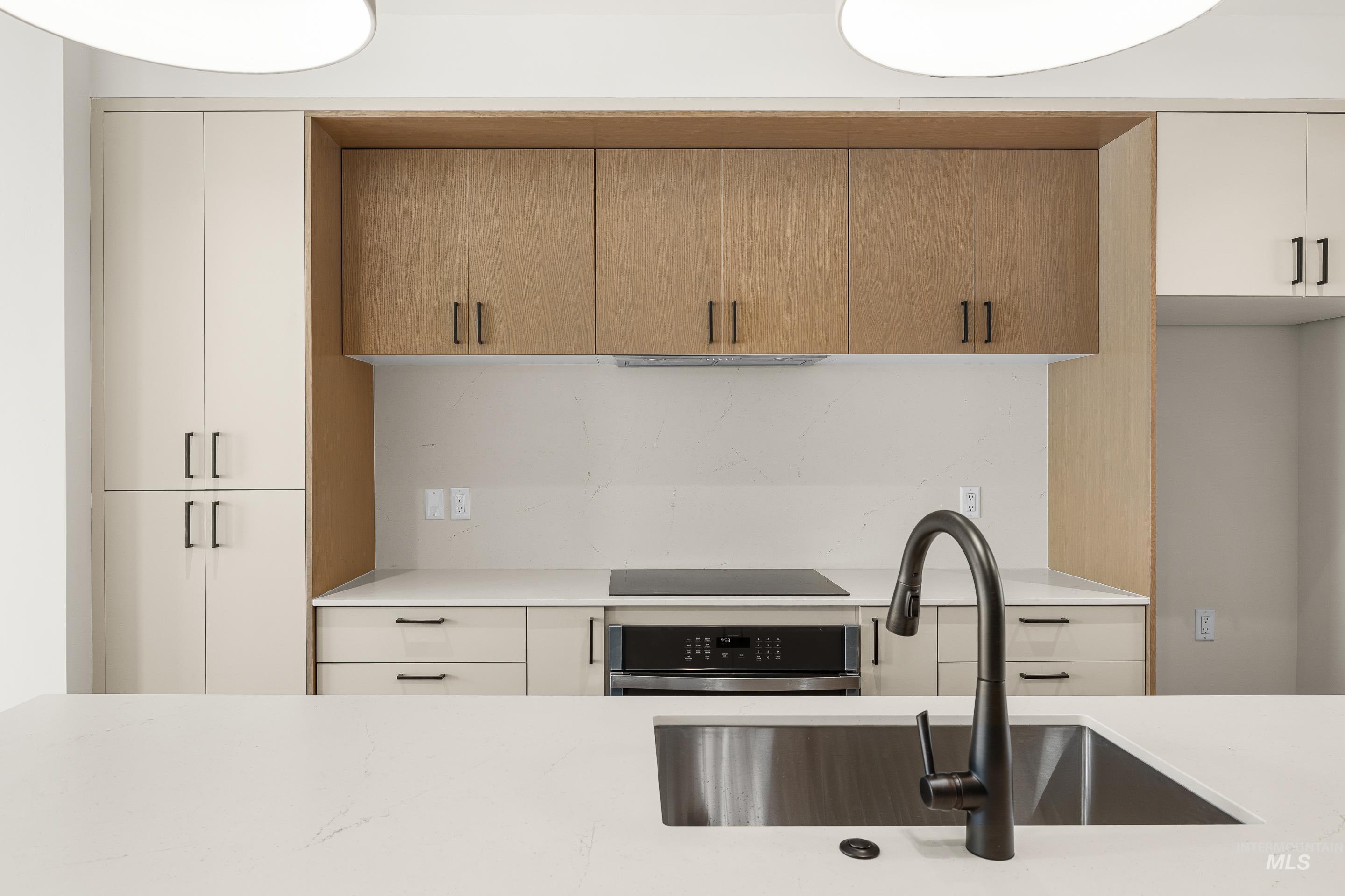 Kitchen featuring oven, light stone countertops, modern cabinets, and black electric cooktop