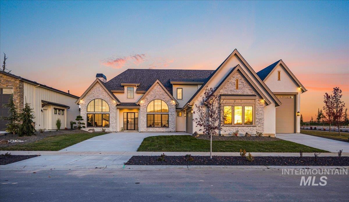 French provincial home featuring stone siding, driveway, a chimney, and an attached garage