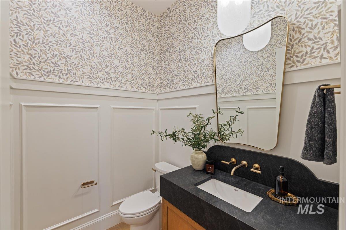 Bathroom with a decorative wall, wainscoting, and vanity