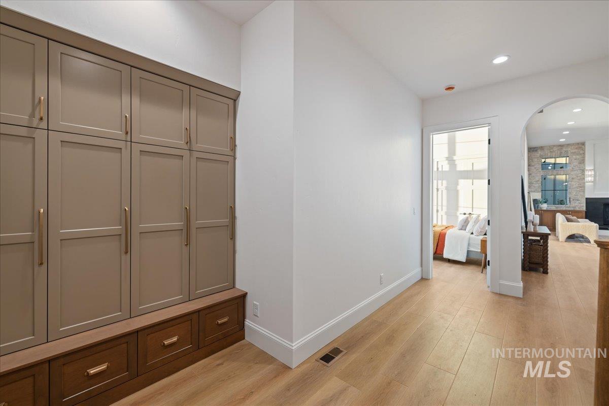 Mudroom with light wood-style floors, recessed lighting, and arched walkways