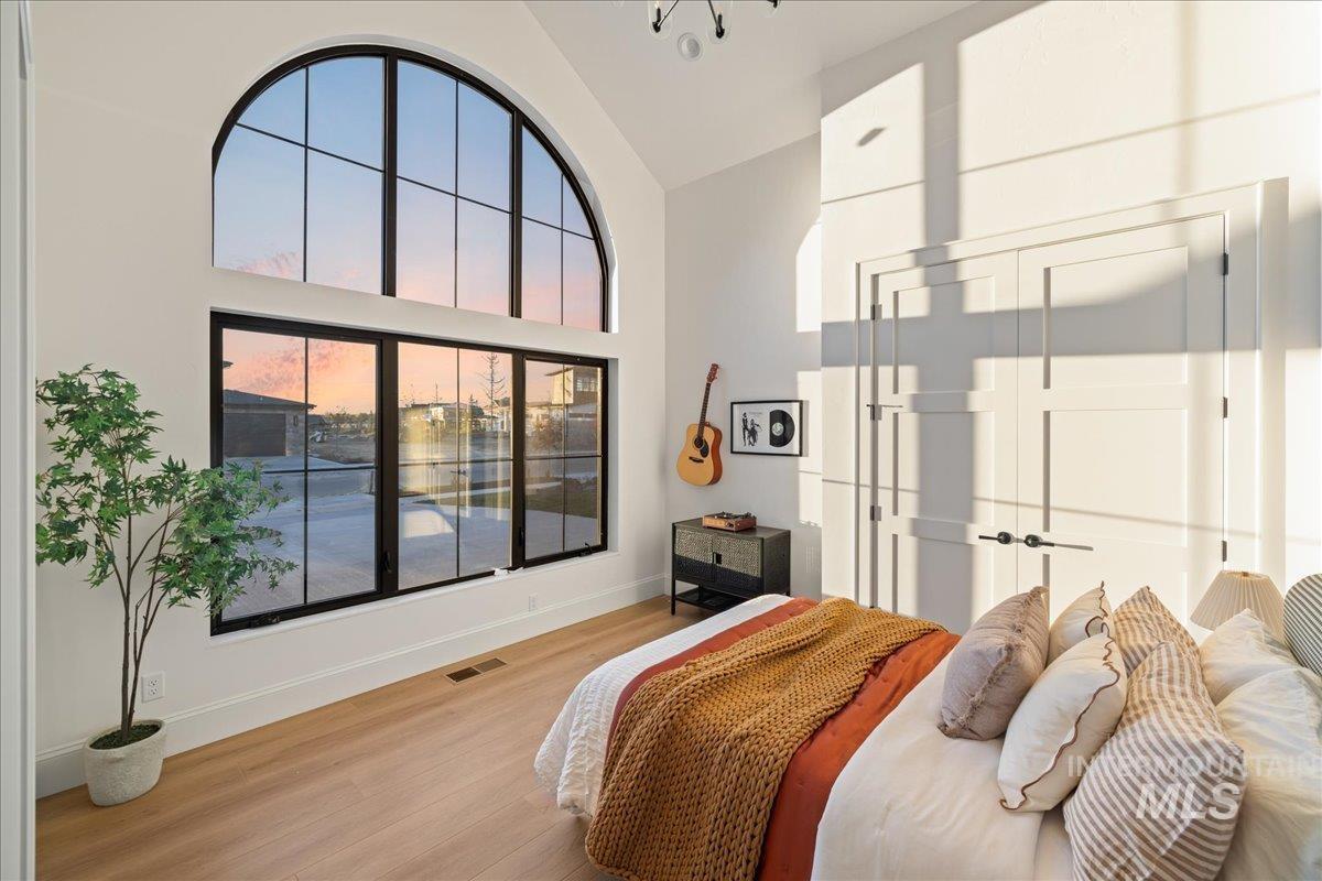 Bedroom with high vaulted ceiling, wood finished floors, and a closet