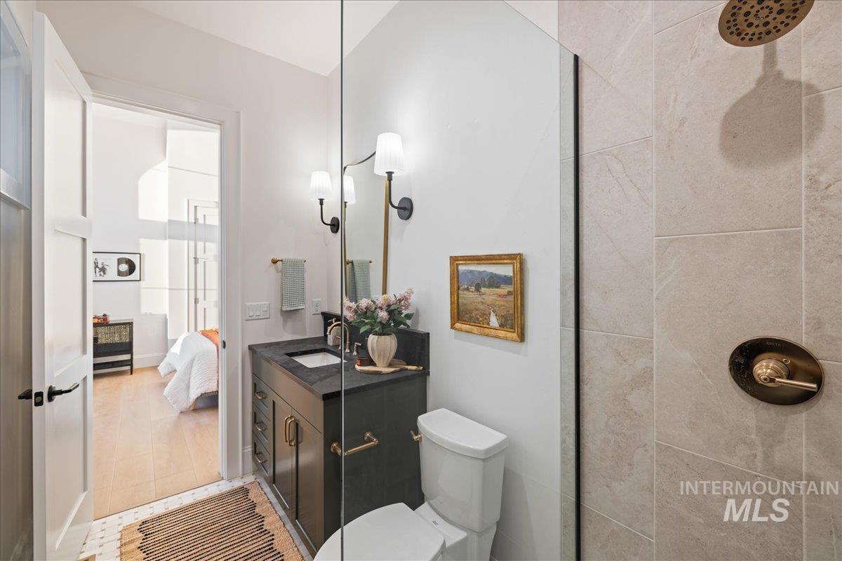 Full bath with vanity, connected bathroom, and tiled shower