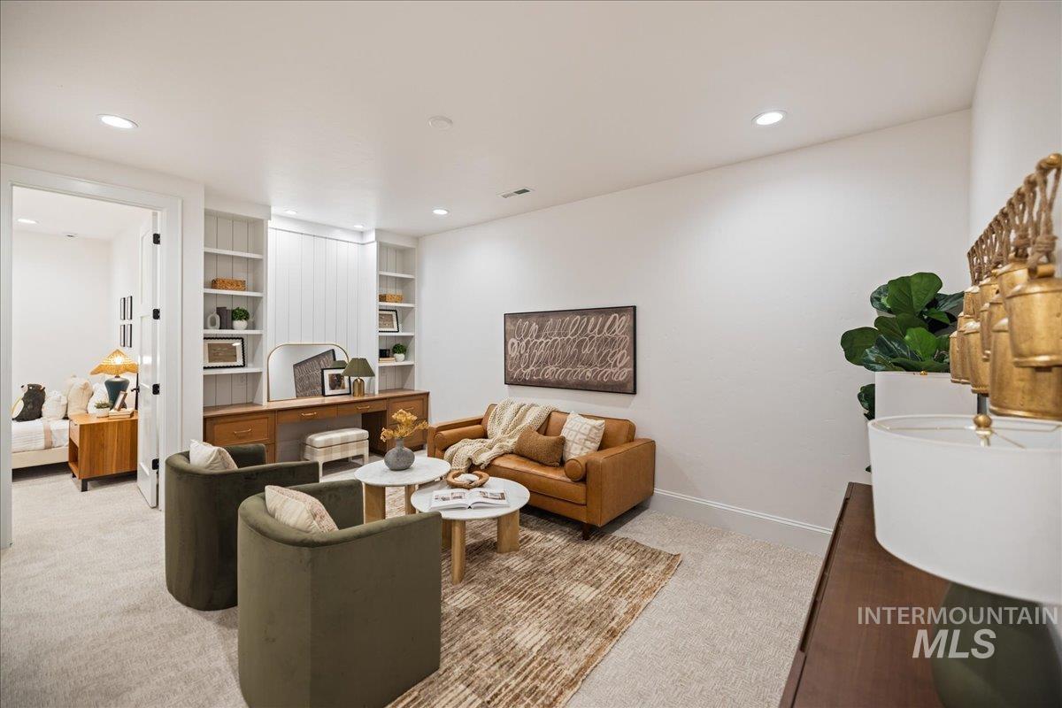 Living room with light carpet, built in shelves, and recessed lighting