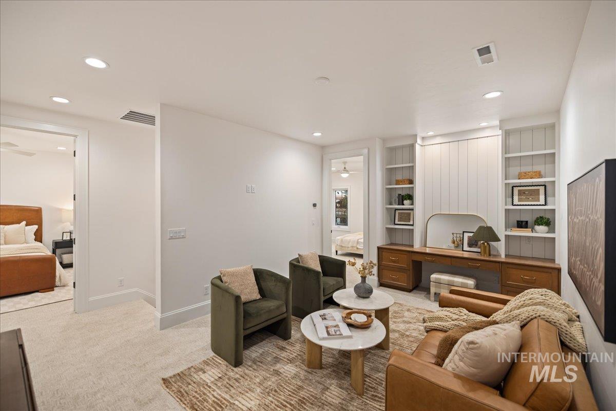 Living area featuring light colored carpet, ceiling fan, built in features, and recessed lighting