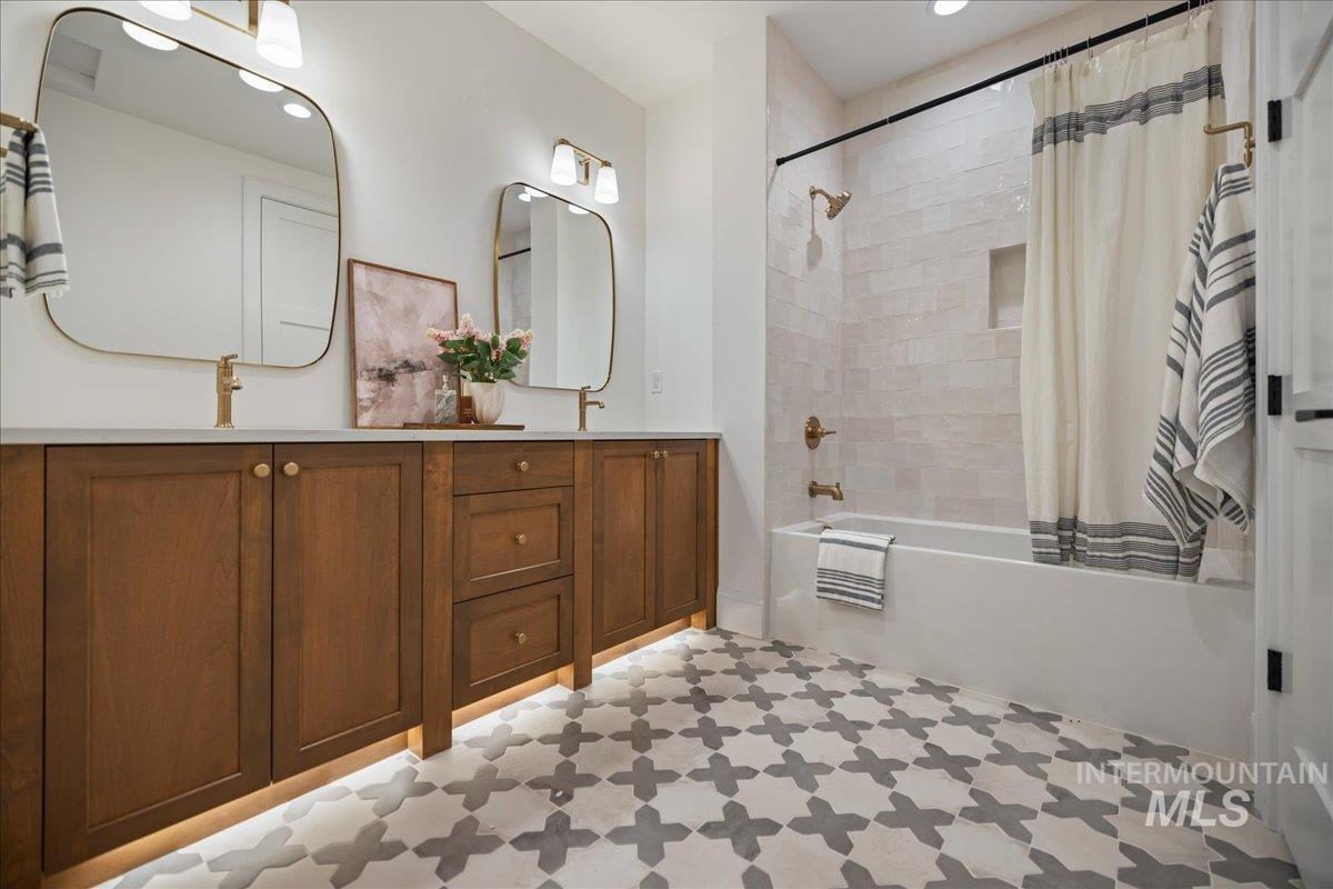 Bathroom featuring light flooring, shower / tub combo, and double vanity