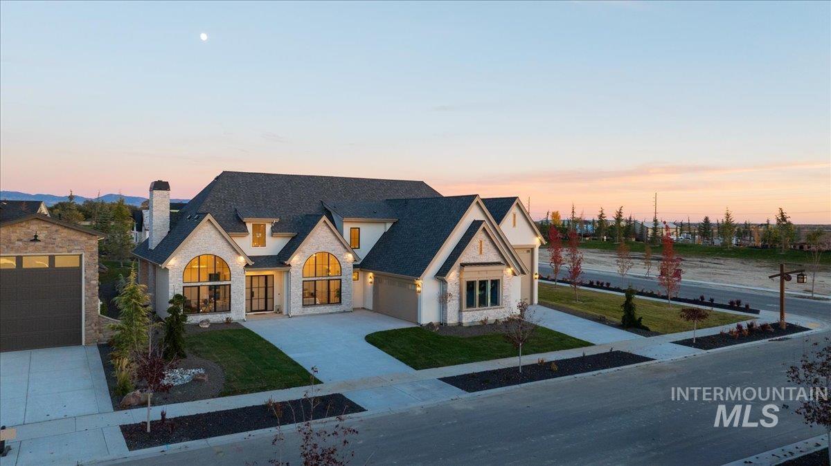 French provincial home with stone siding, a front yard, a chimney, and driveway