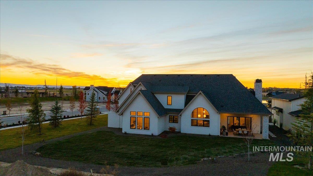 Rear view of property with a yard, stucco siding, a patio area, and a chimney