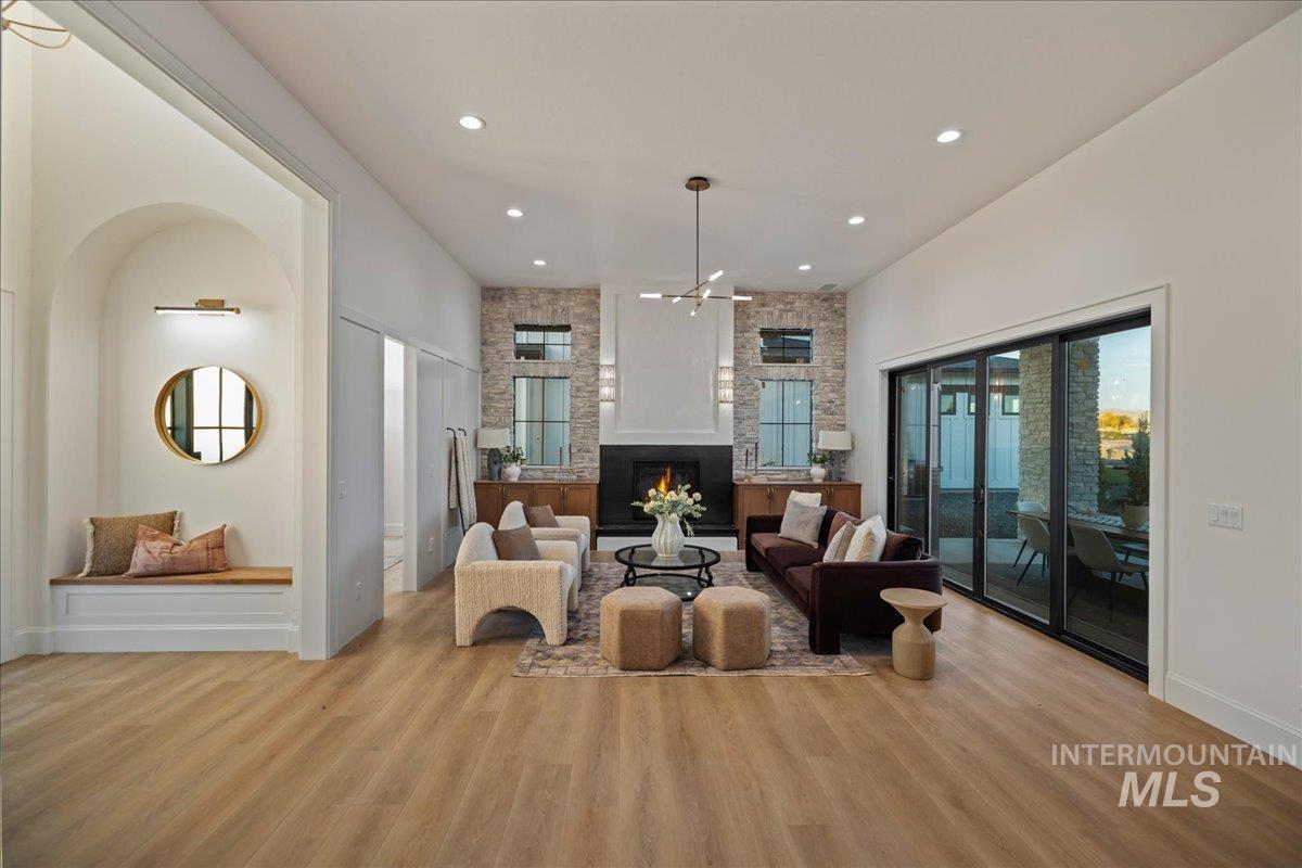 Living room with a fireplace, wood finished floors, recessed lighting, and a towering ceiling