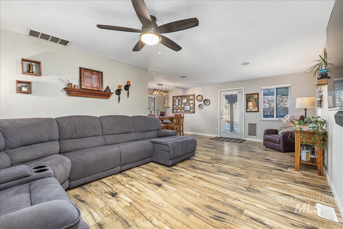 Living room featuring light wood-type flooring, ceiling fan, and plenty of natural light
