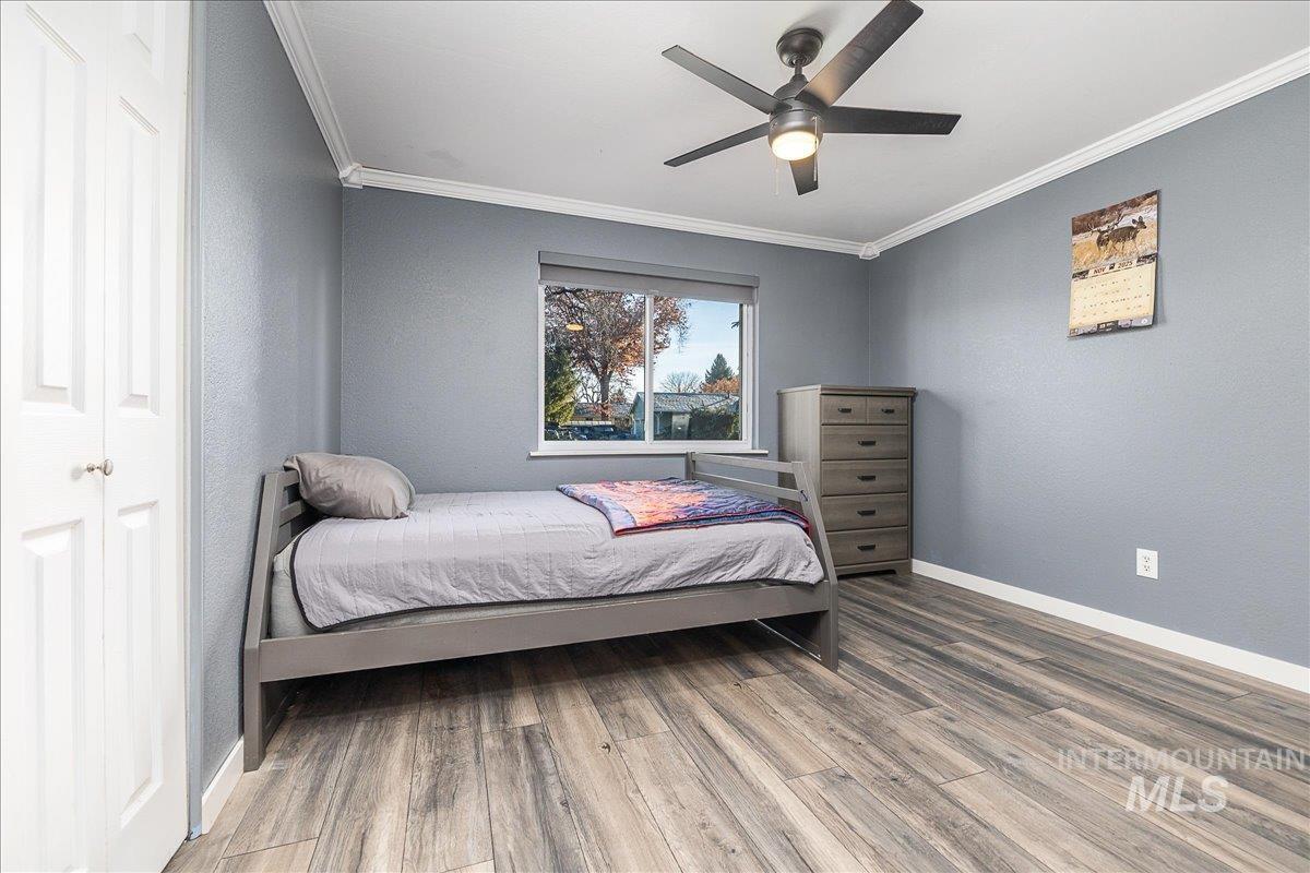 Bedroom featuring wood finished floors, ornamental molding, ceiling fan, and a textured wall