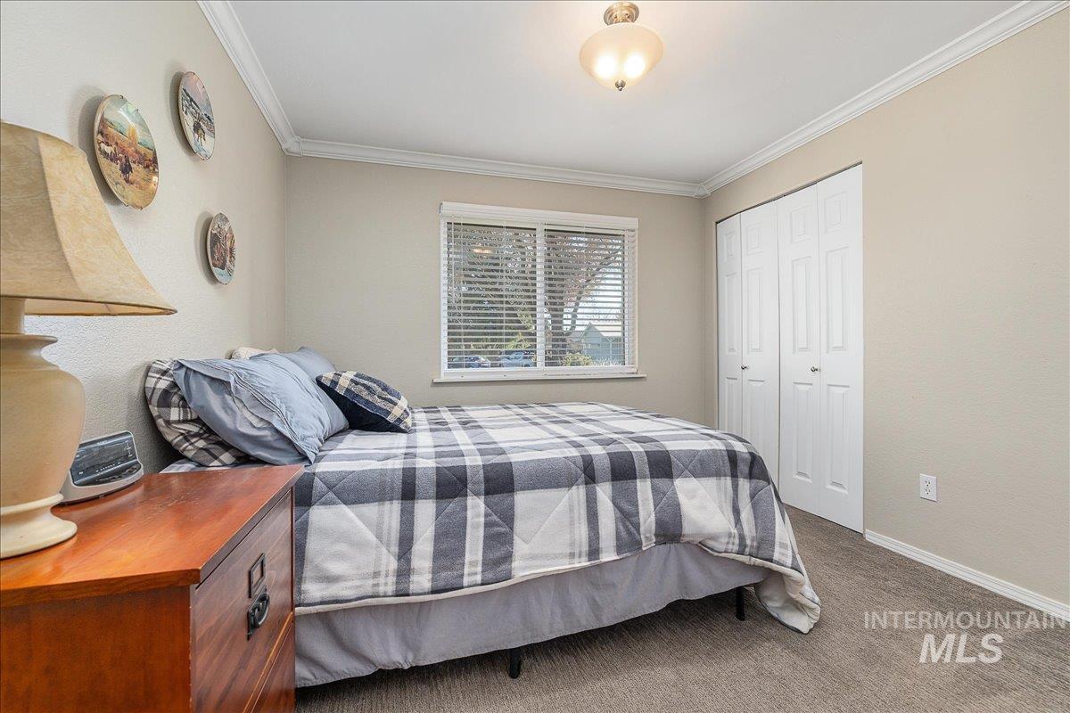 Bedroom featuring dark colored carpet, a closet, ornamental molding, and a textured wall