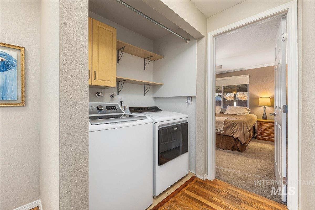 Laundry area featuring light wood-style floors, washing machine and dryer, light carpet, cabinet space, and ornamental molding