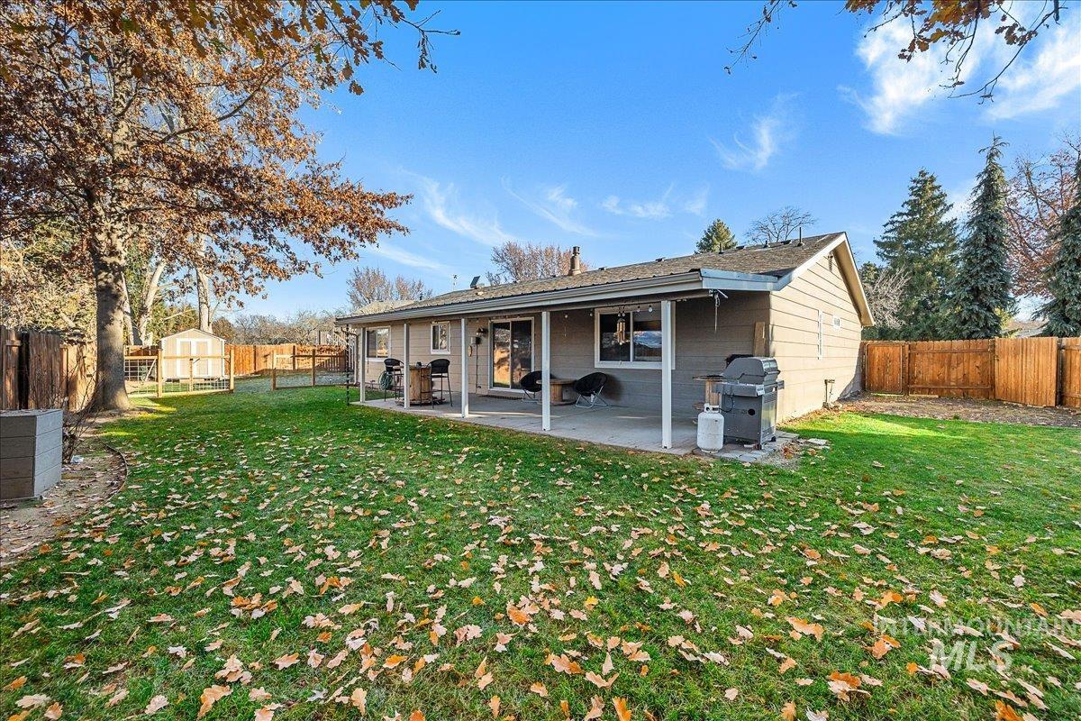 Rear view of house featuring a fenced backyard, a patio area, and a shed