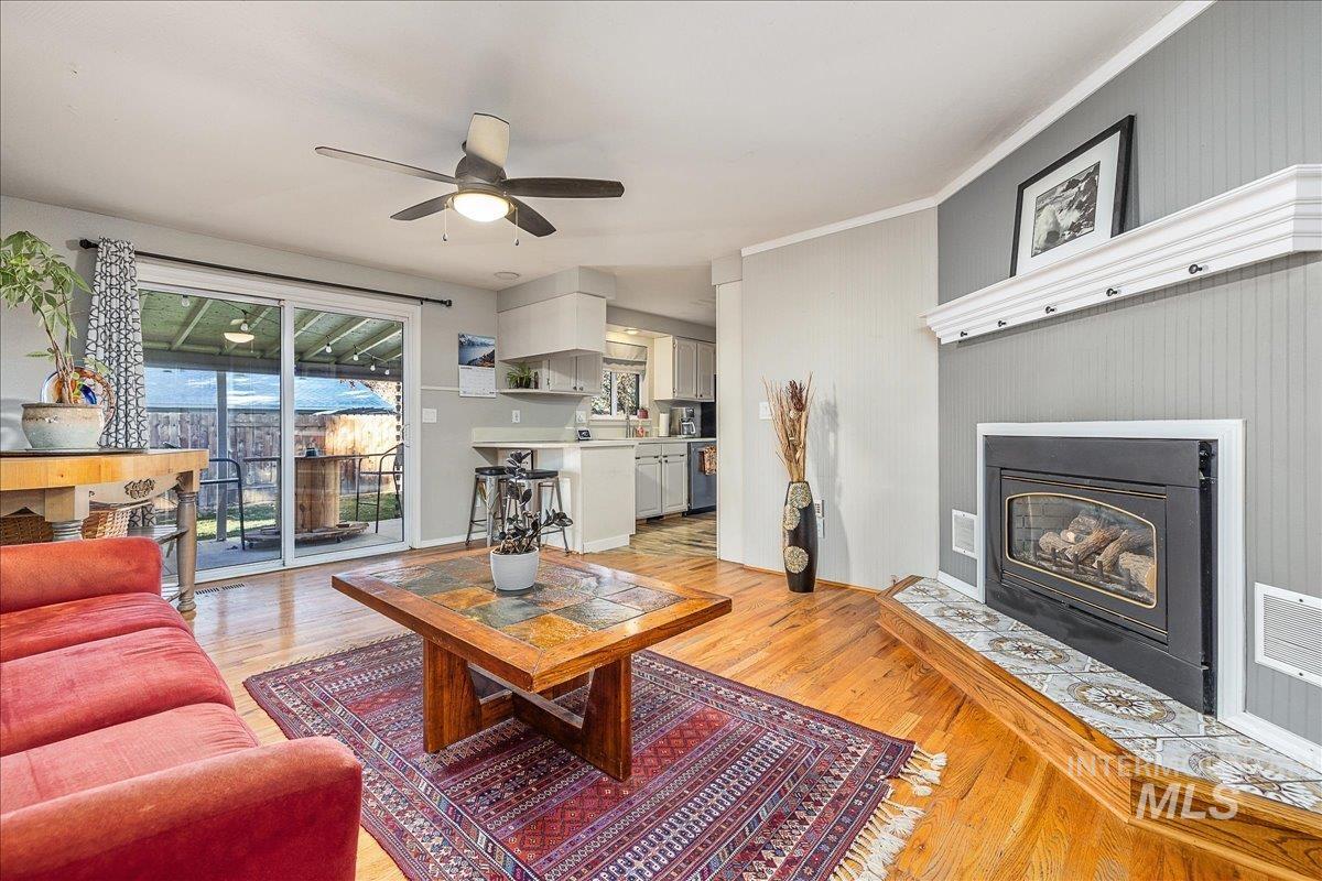 Living area featuring a fireplace with flush hearth, light wood finished floors, and a ceiling fan