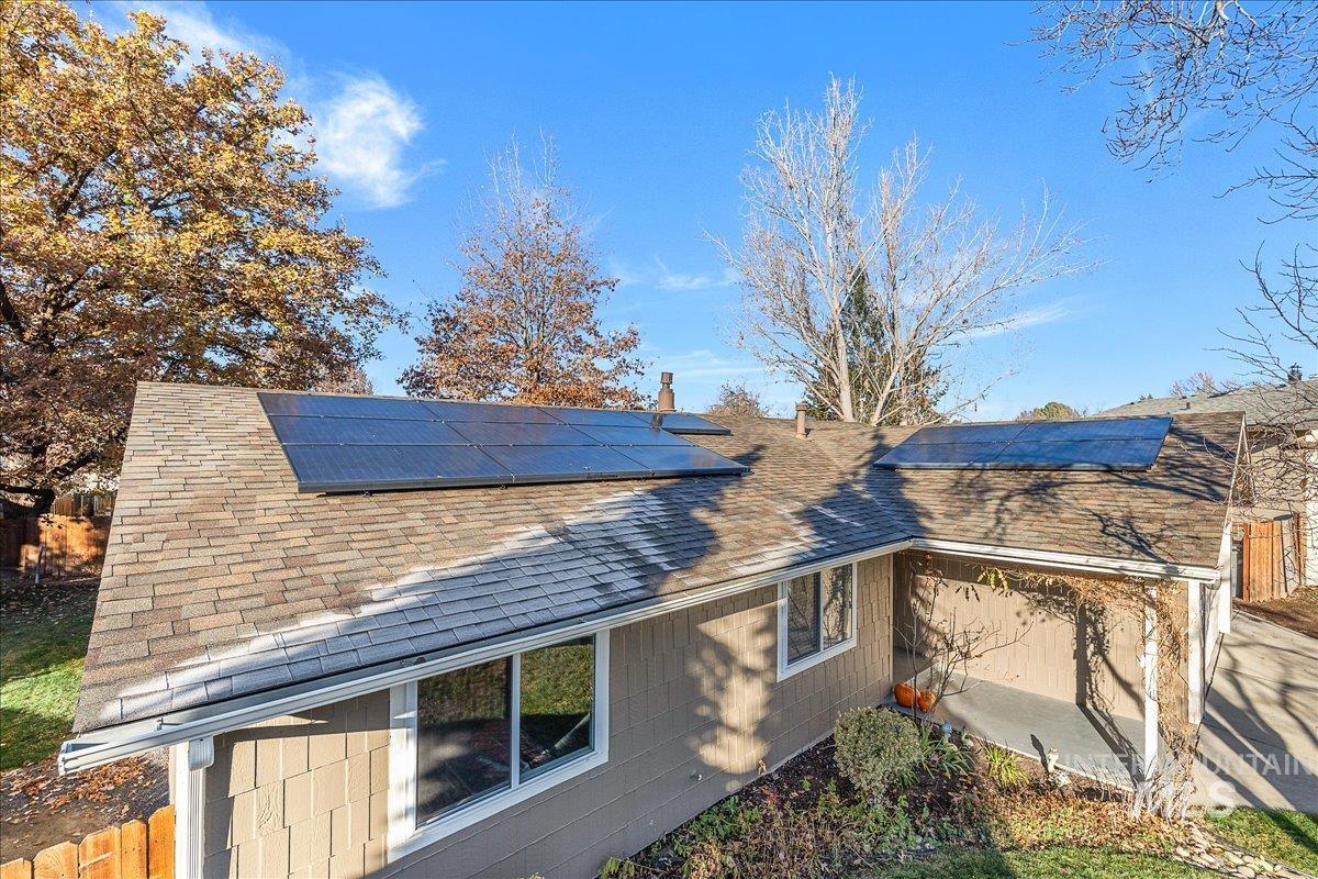 View of property exterior with a shingled roof and solar panels