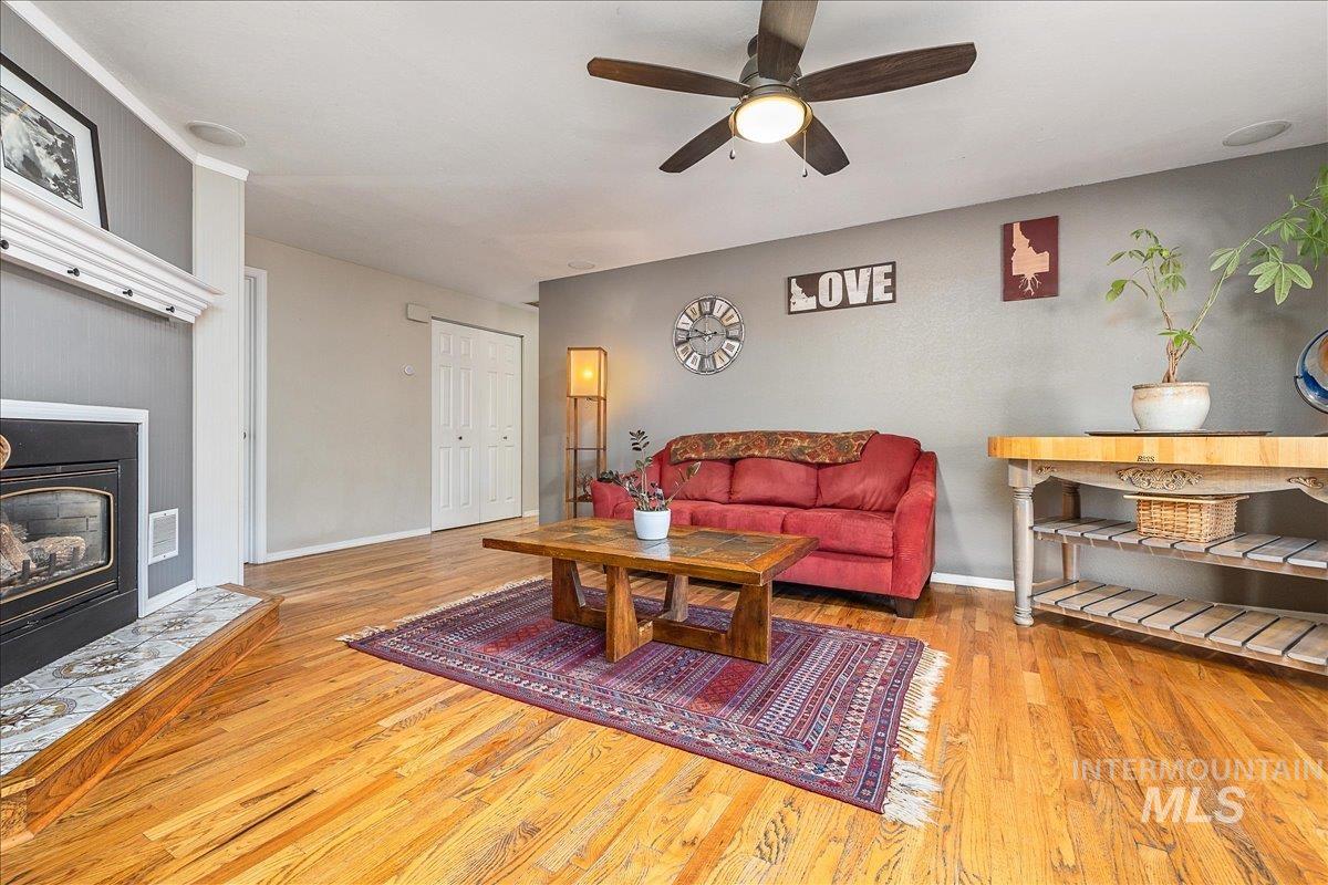 Living room featuring a fireplace, light wood finished floors, and a ceiling fan