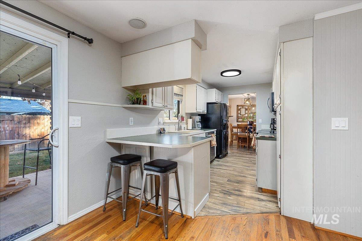 Kitchen featuring a breakfast bar, white cabinetry, light wood finished floors, light countertops, and open shelves