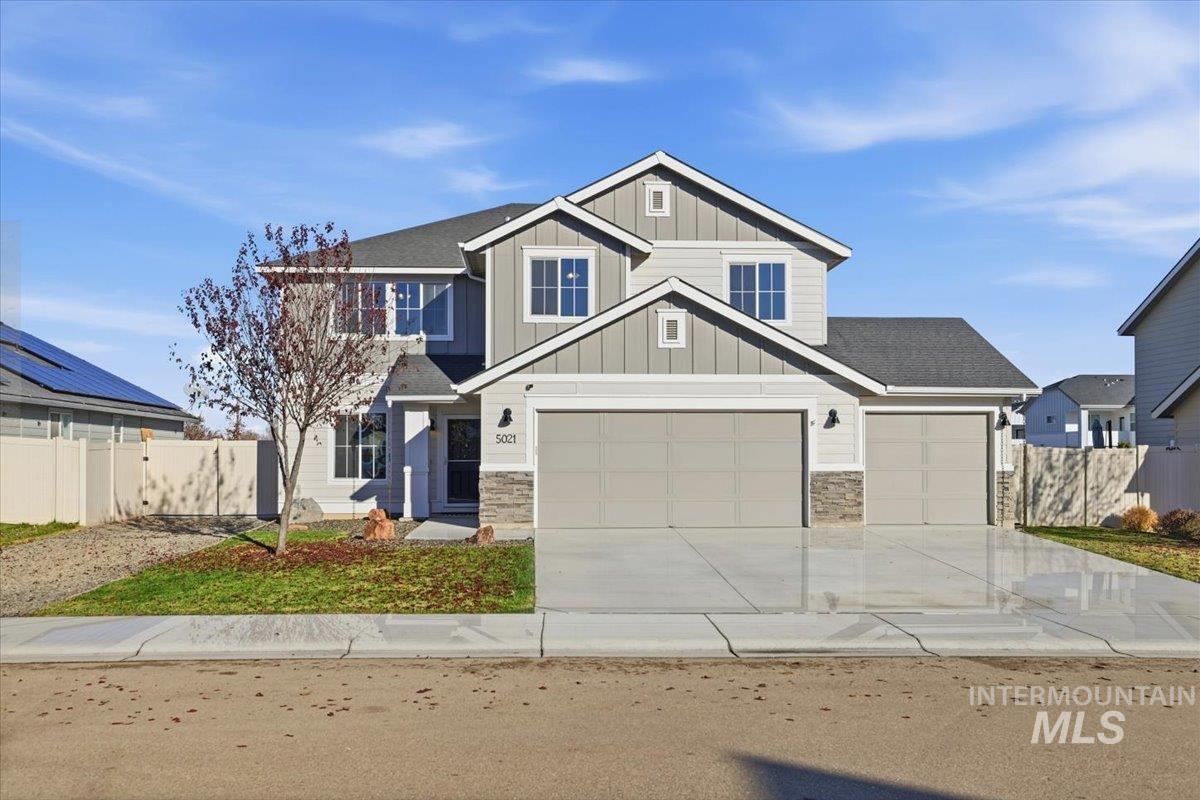 View of front of property featuring board and batten siding, stone siding, driveway, and a shingled roof