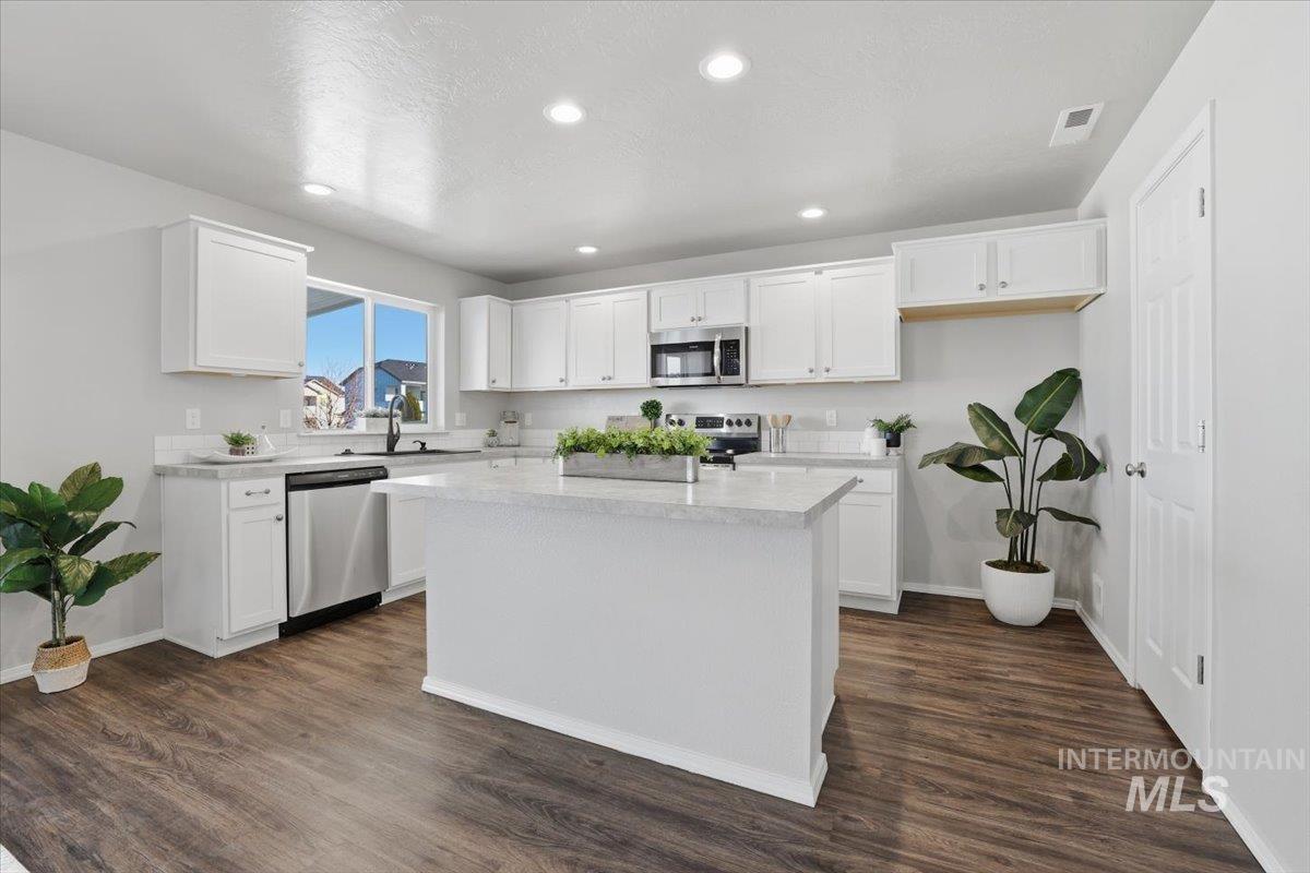 Kitchen with white cabinetry, appliances with stainless steel finishes, recessed lighting, a center island, and dark wood-style floors